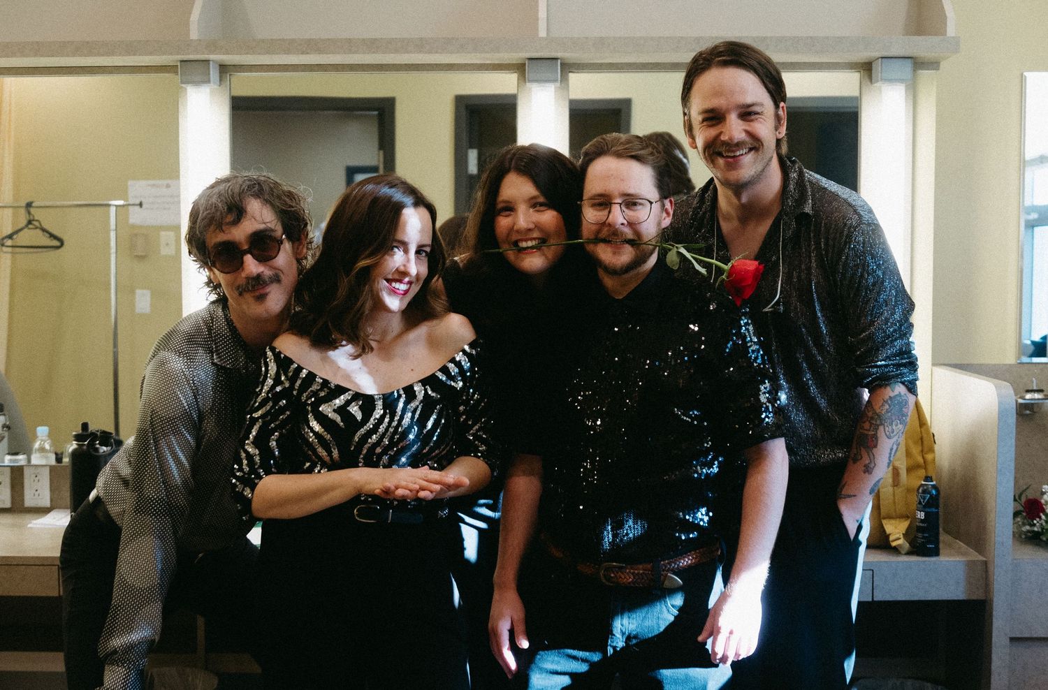 A group of people posing together in an indoor setting, smiling and embracing in a casual gathering.
