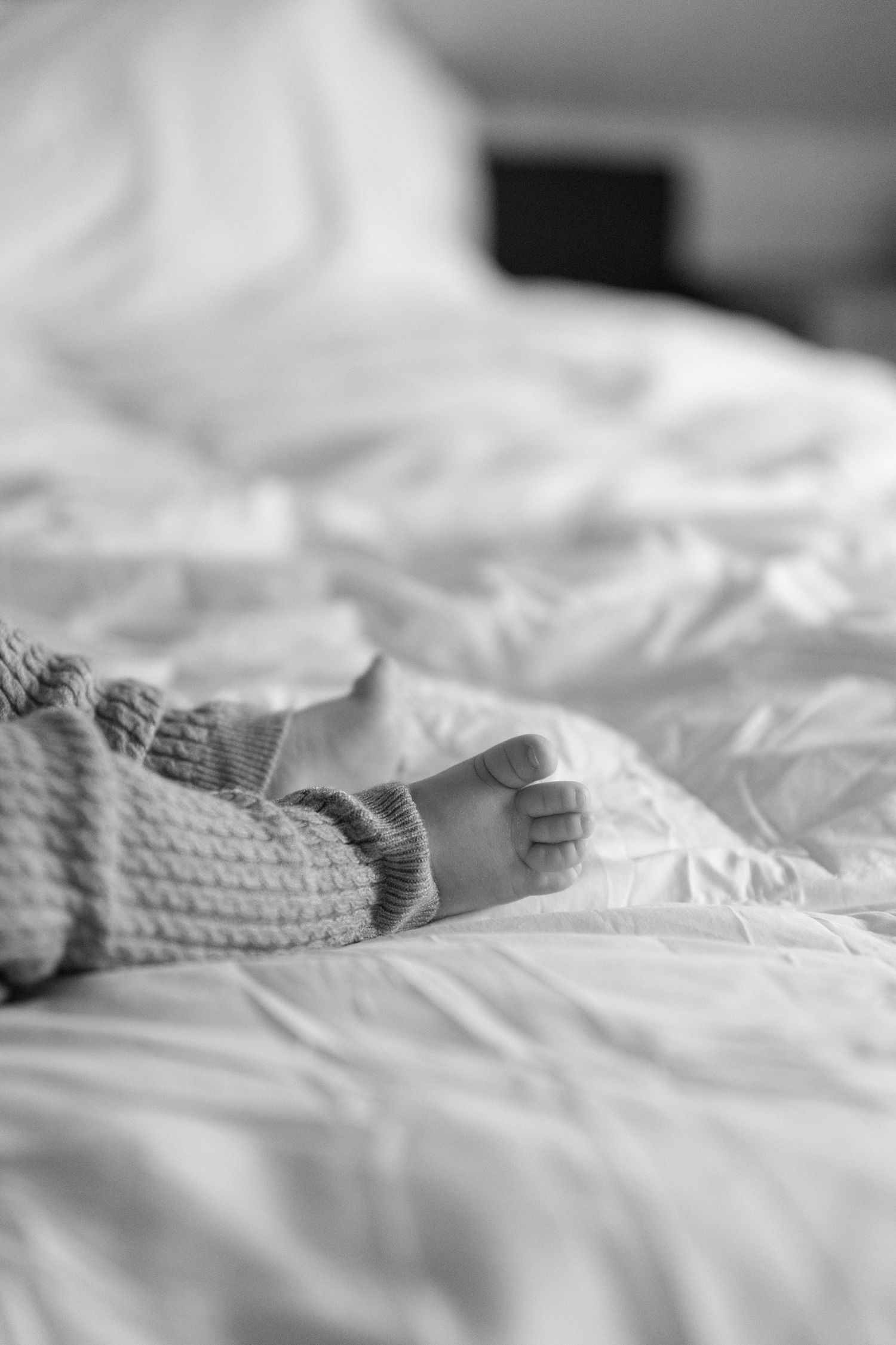Close-up black and white photo of rumpled white bedding and textured fabric.