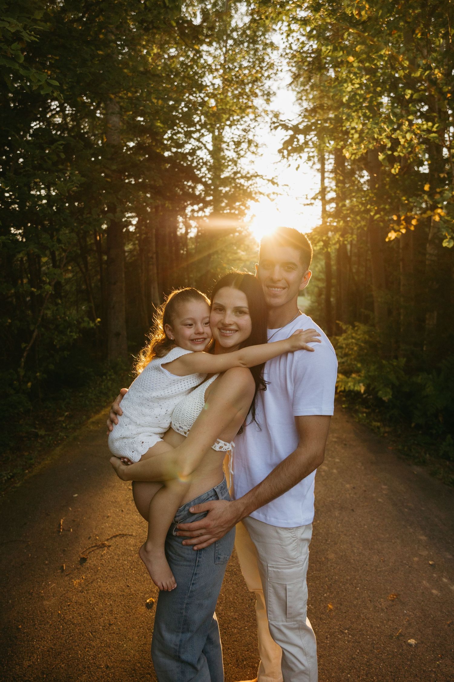 A loving family moment captured on a tree-lined path during golden hour sunset.