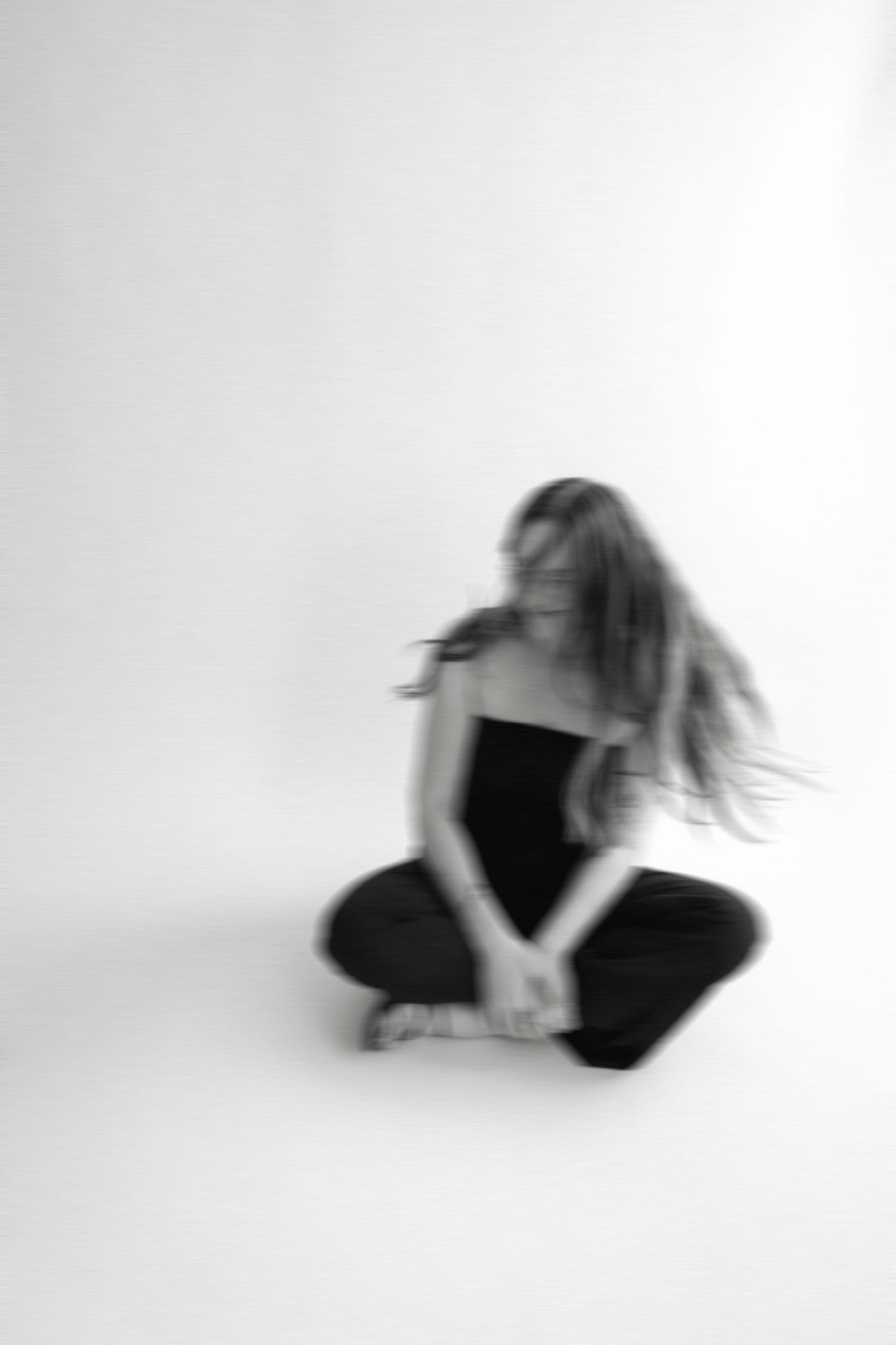 Blurred motion portrait of someone in black clothing against white background.
