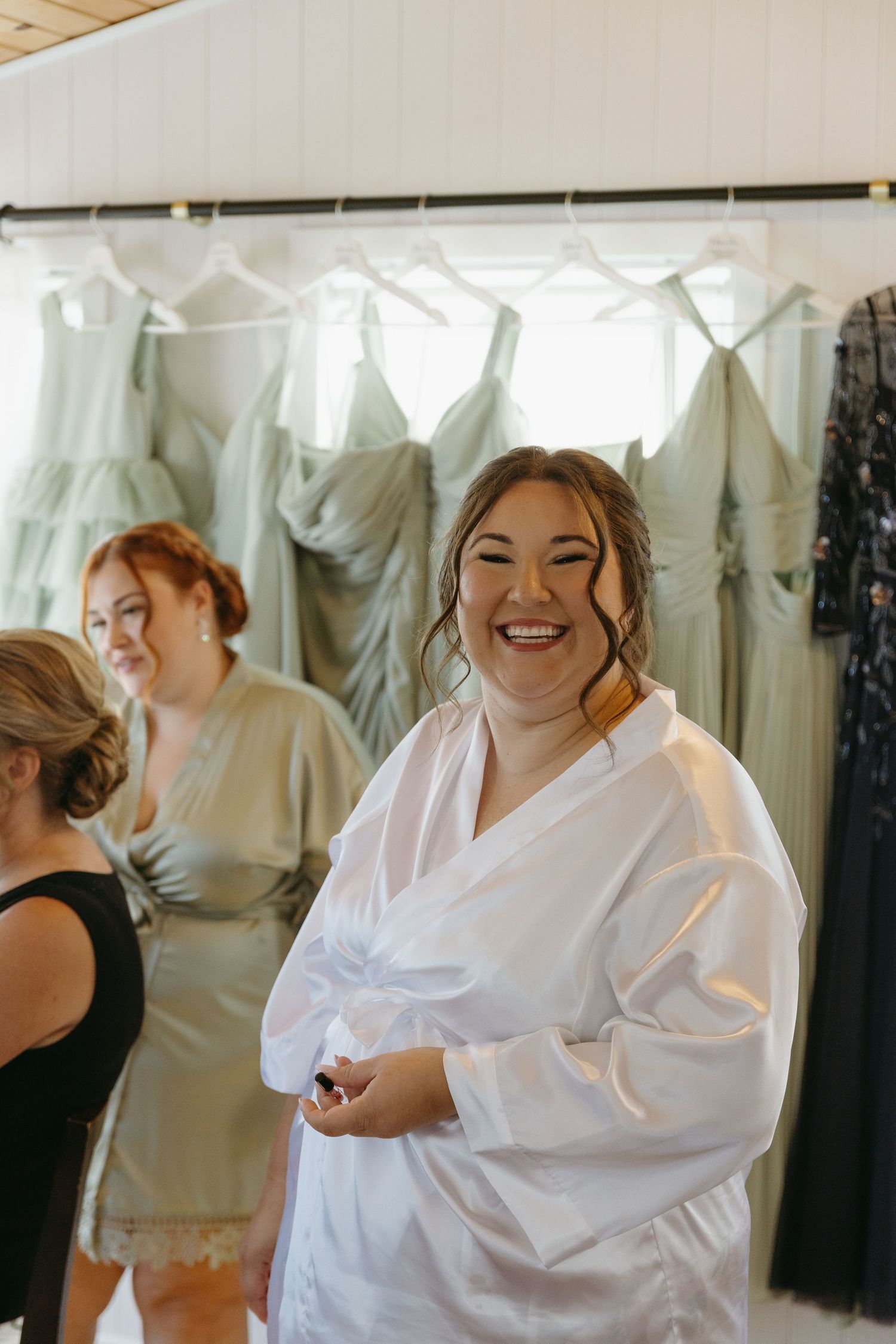 A joyful moment captured in a bridal boutique with white gowns hanging in the background.
