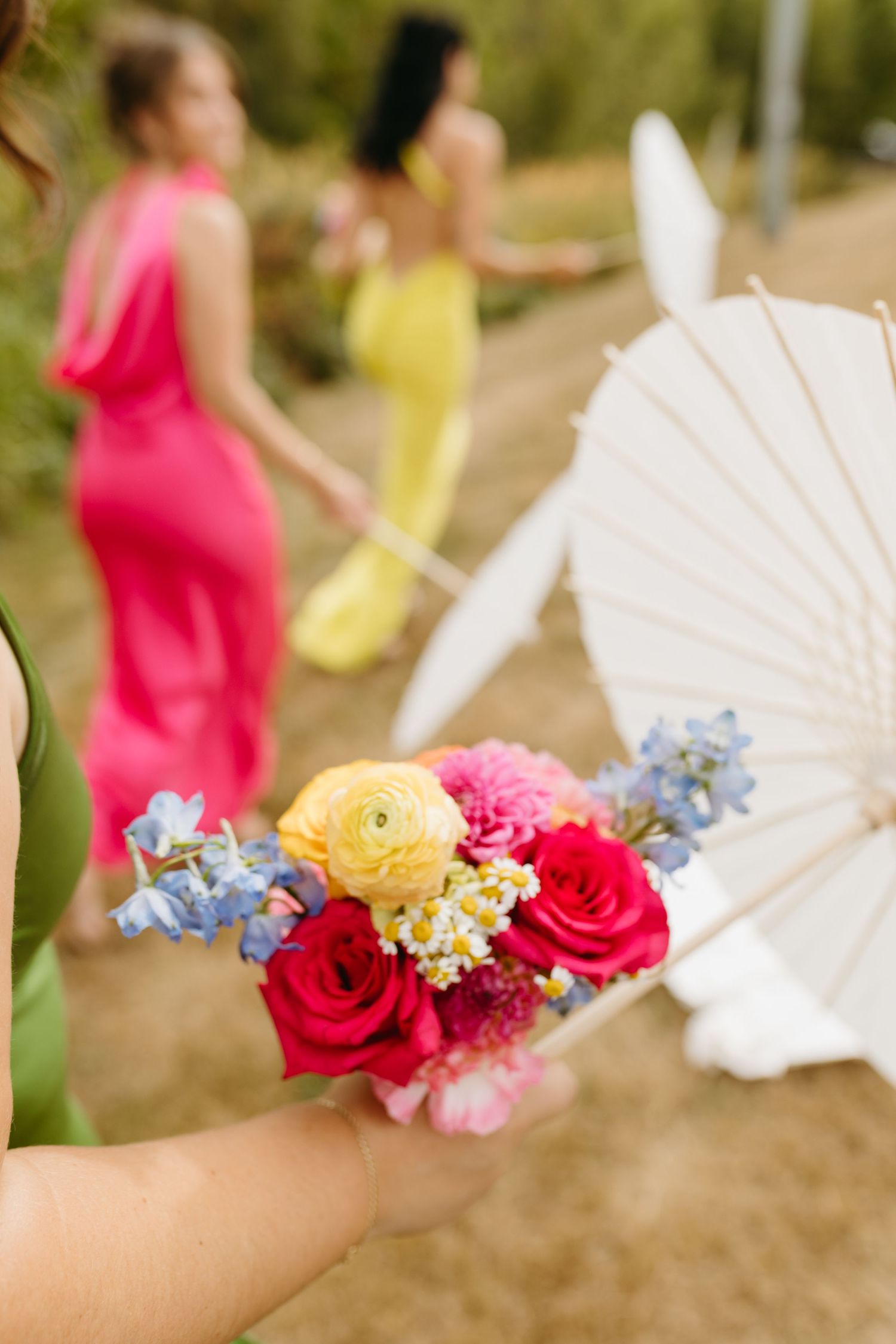 Decorative paper parasols adorned with colorful flowers including red roses, pink blooms and blue delphinium.
