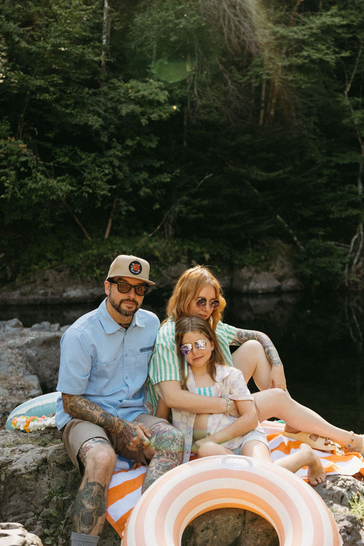 A couple enjoys a romantic picnic by a serene lake with orange and white striped blankets and snacks.