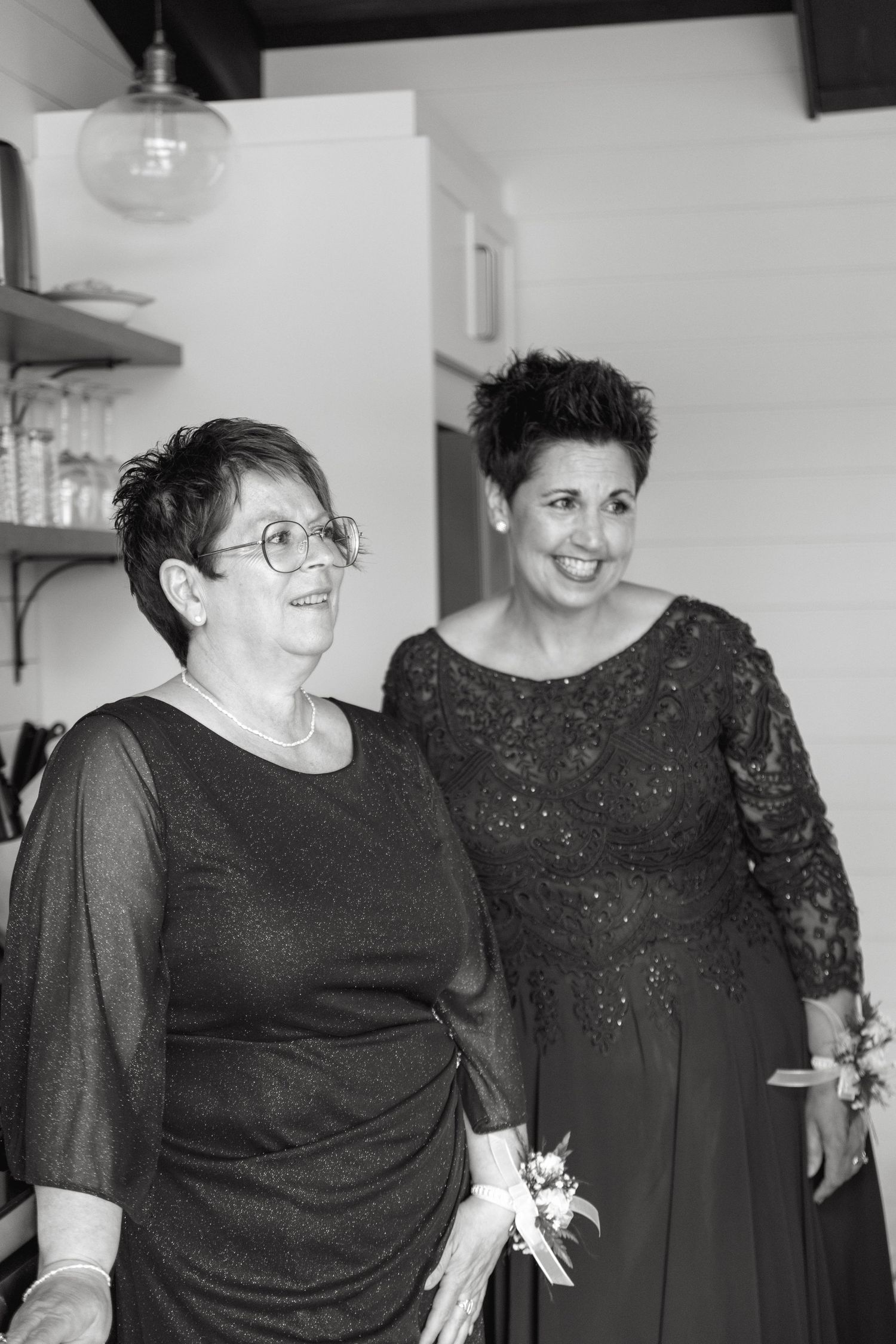 Two people wearing black formal attire share a joyful moment at a special occasion.