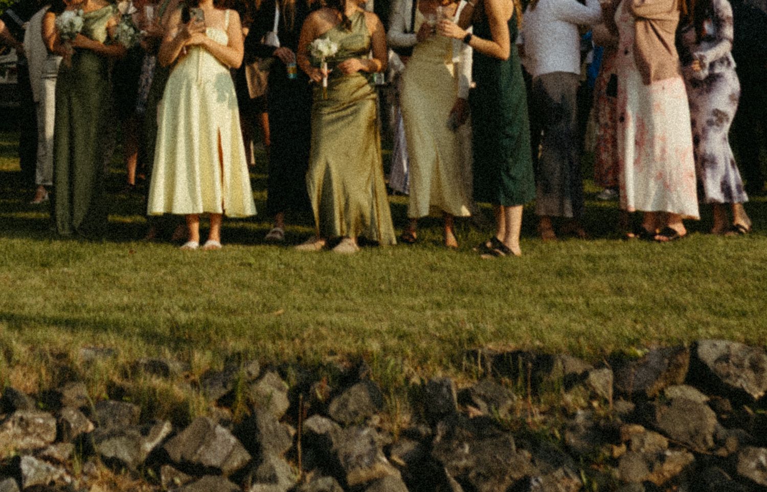 A group of people stand in formal attire on stone steps during an outdoor gathering or celebration.