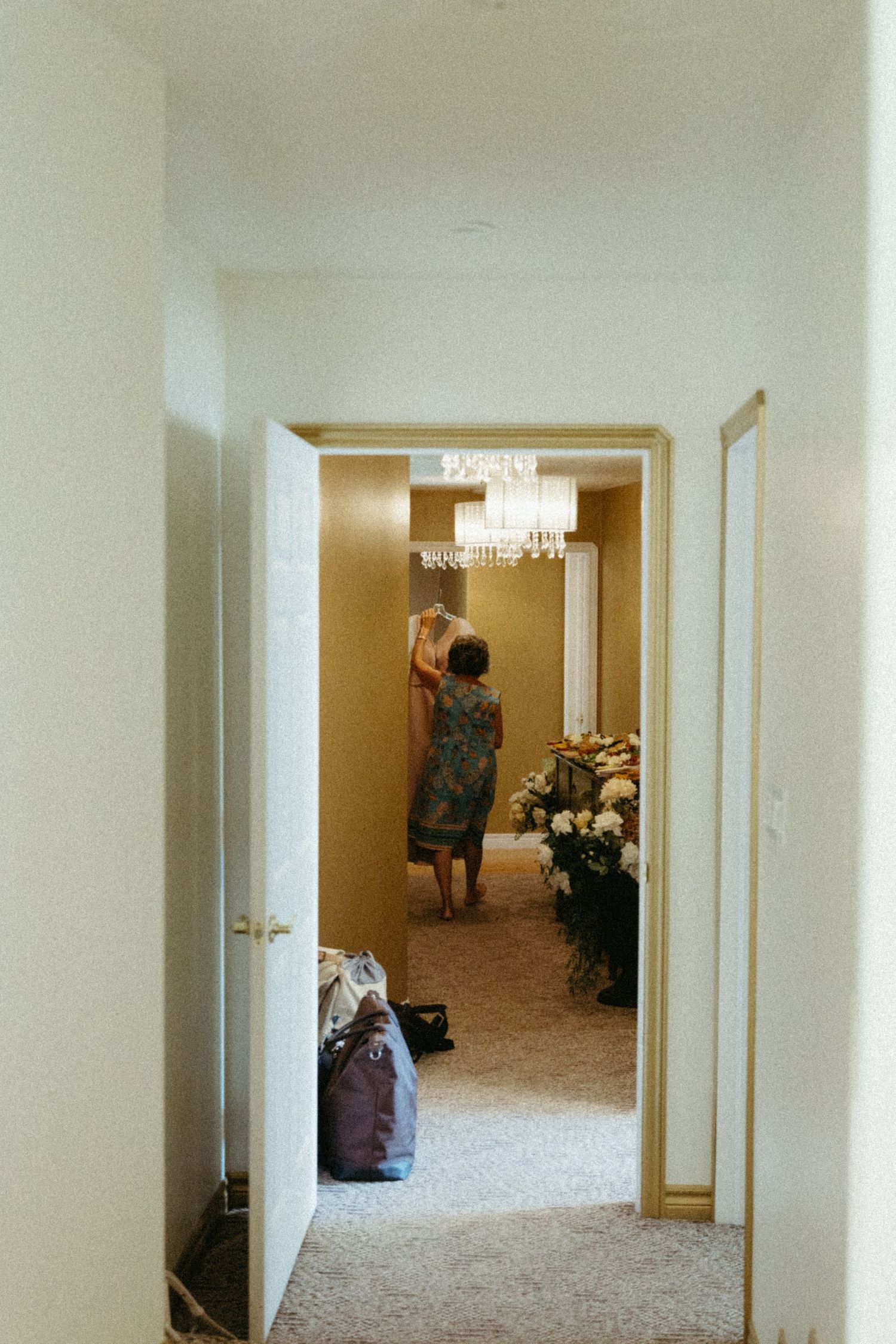 Long empty hallway with white walls, beige carpet, and a figure visible at the far end.