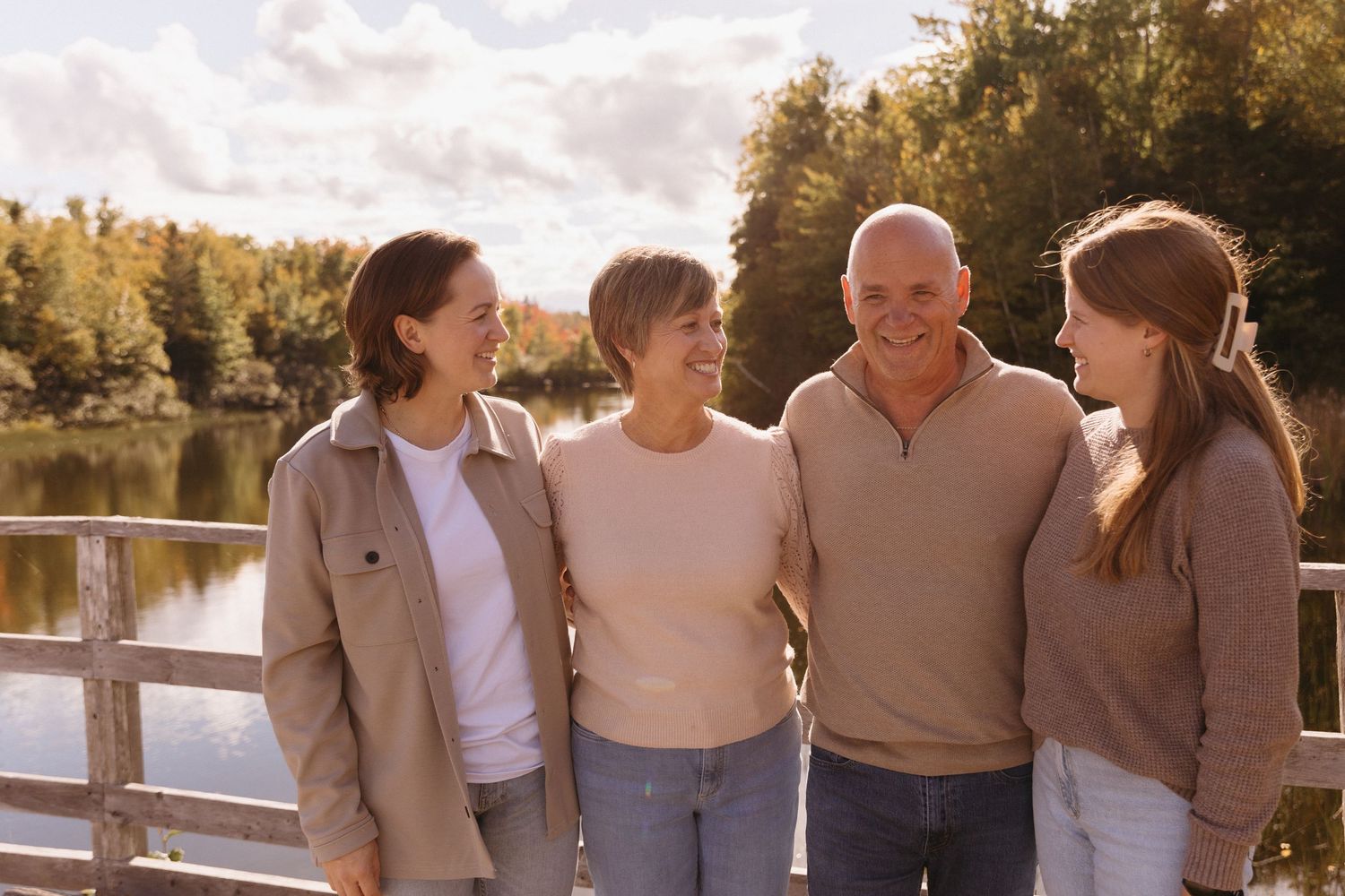 Family members pose together in casual attire along a waterfront during golden hour.