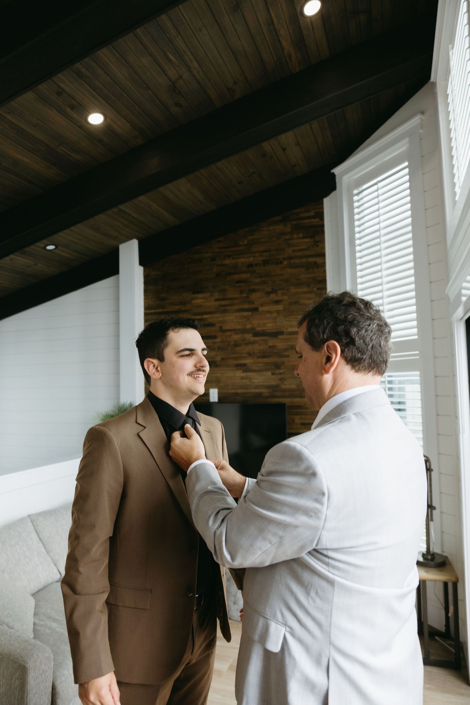 A sequence of candid moments between two people in formal attire interacting in a rustic interior space.