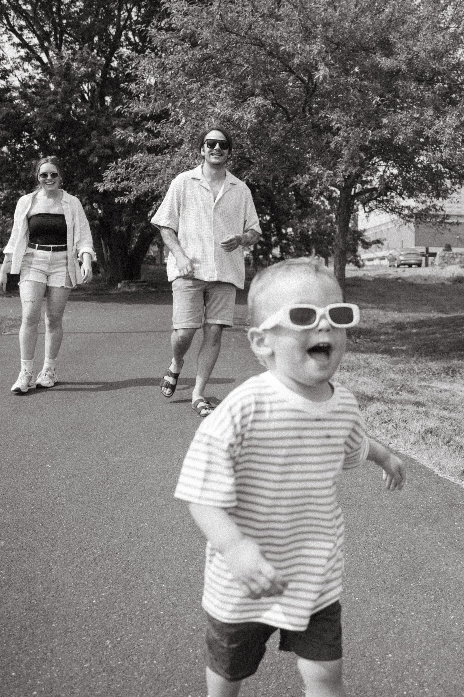 Joyful child in striped shirt and sunglasses running outdoors on summer day.