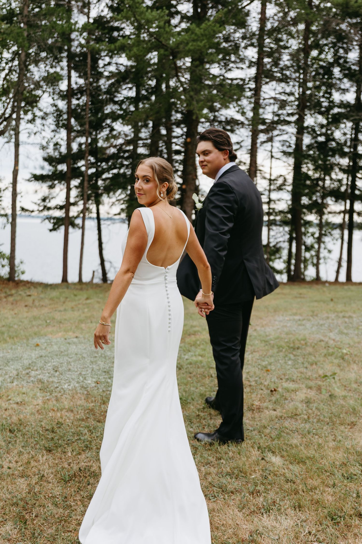 A series of four wedding photos showing a couple in formal attire walking together on a grassy hillside with pine trees.