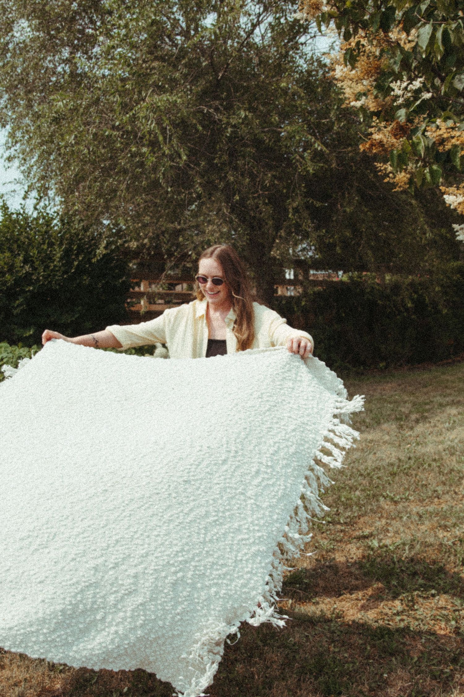 A large white textured fabric or paper being displayed outdoors against an autumn background.