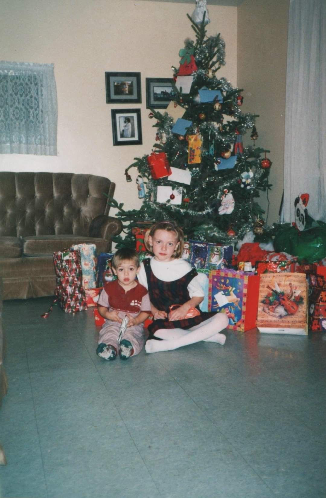 Christmas morning scene with decorated tree and wrapped presents scattered across a carpeted living room floor.