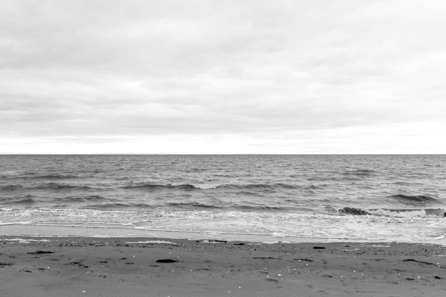 Minimalist black and white seascape with cloudy horizon over ocean waves.