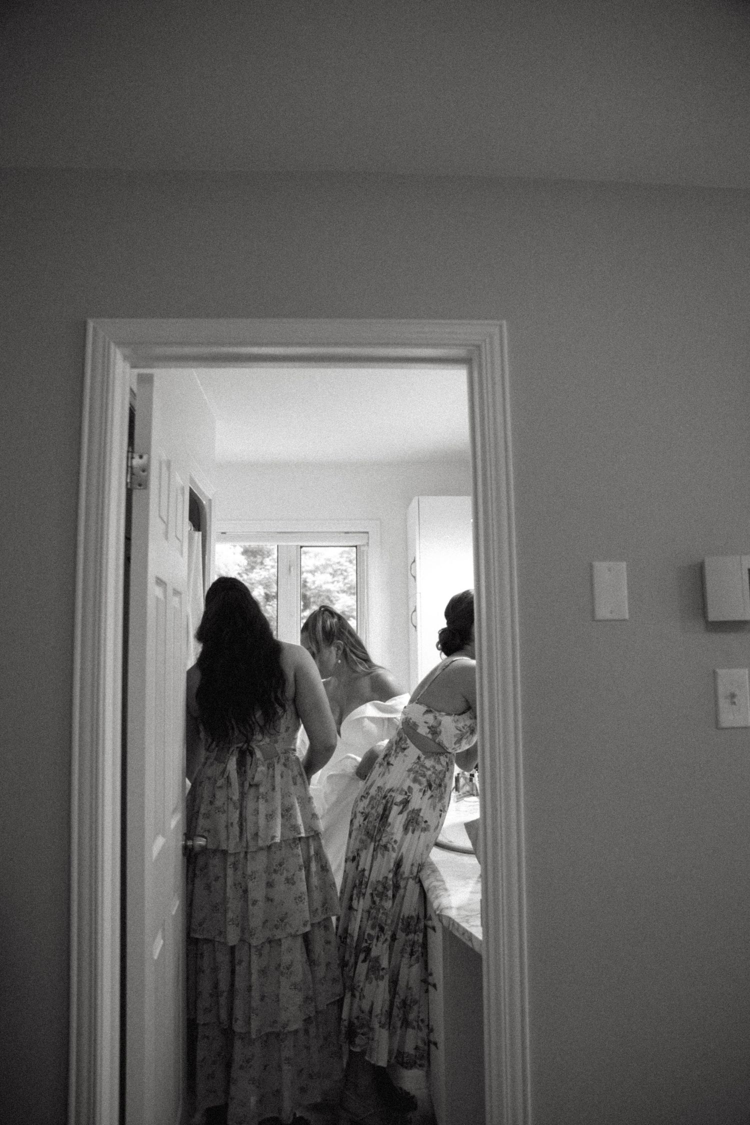 Silhouettes moving through doorways in a dimly lit interior hallway.