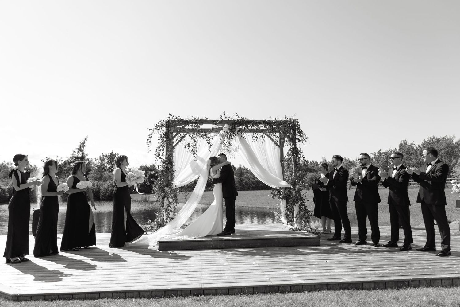 A series of black and white wedding ceremony photos showing guests and wedding party arranged in formal poses outdoors.