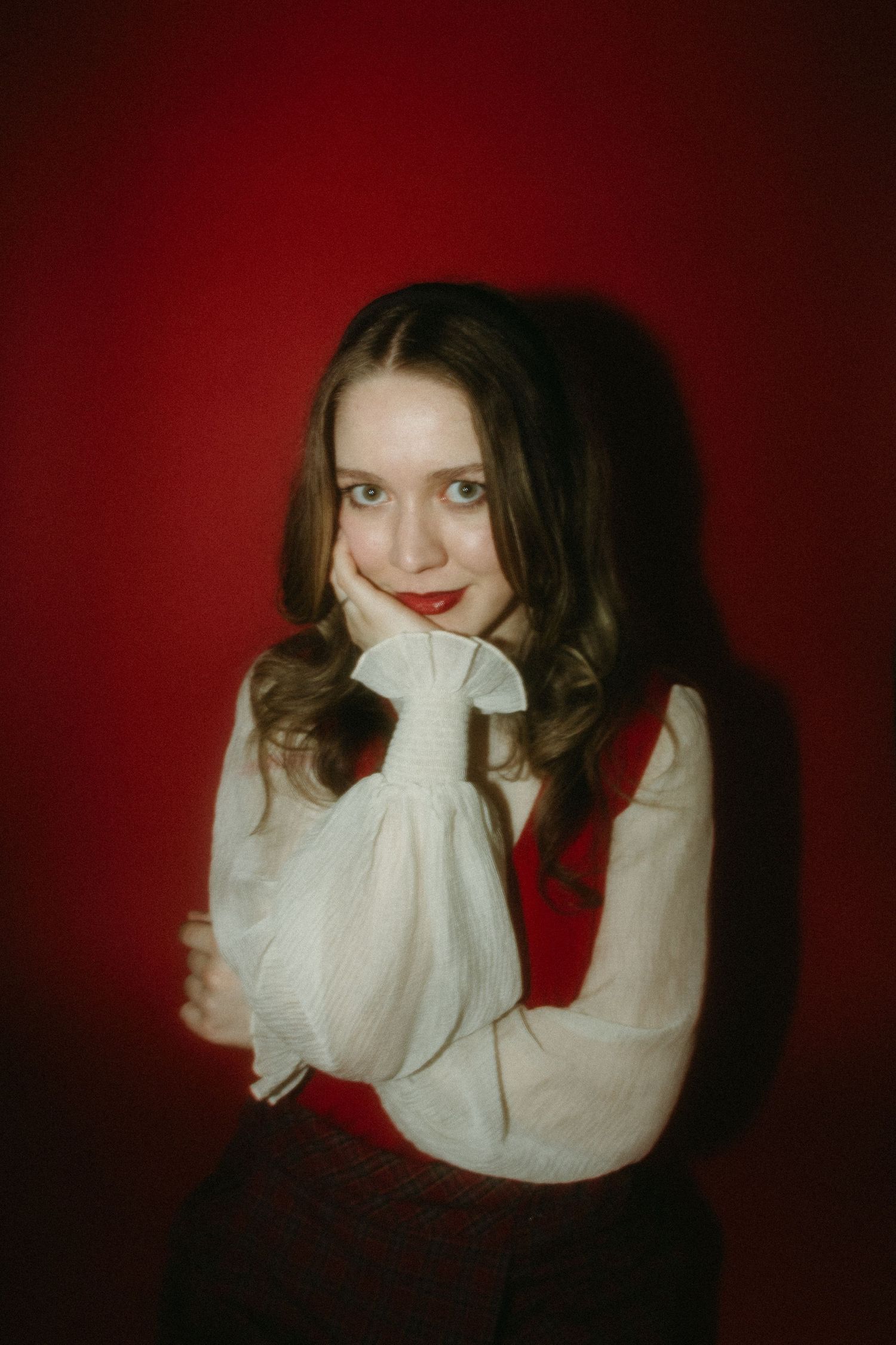 A sequence of six moody portraits against a dark red background shows someone in a white sweater making expressive poses.