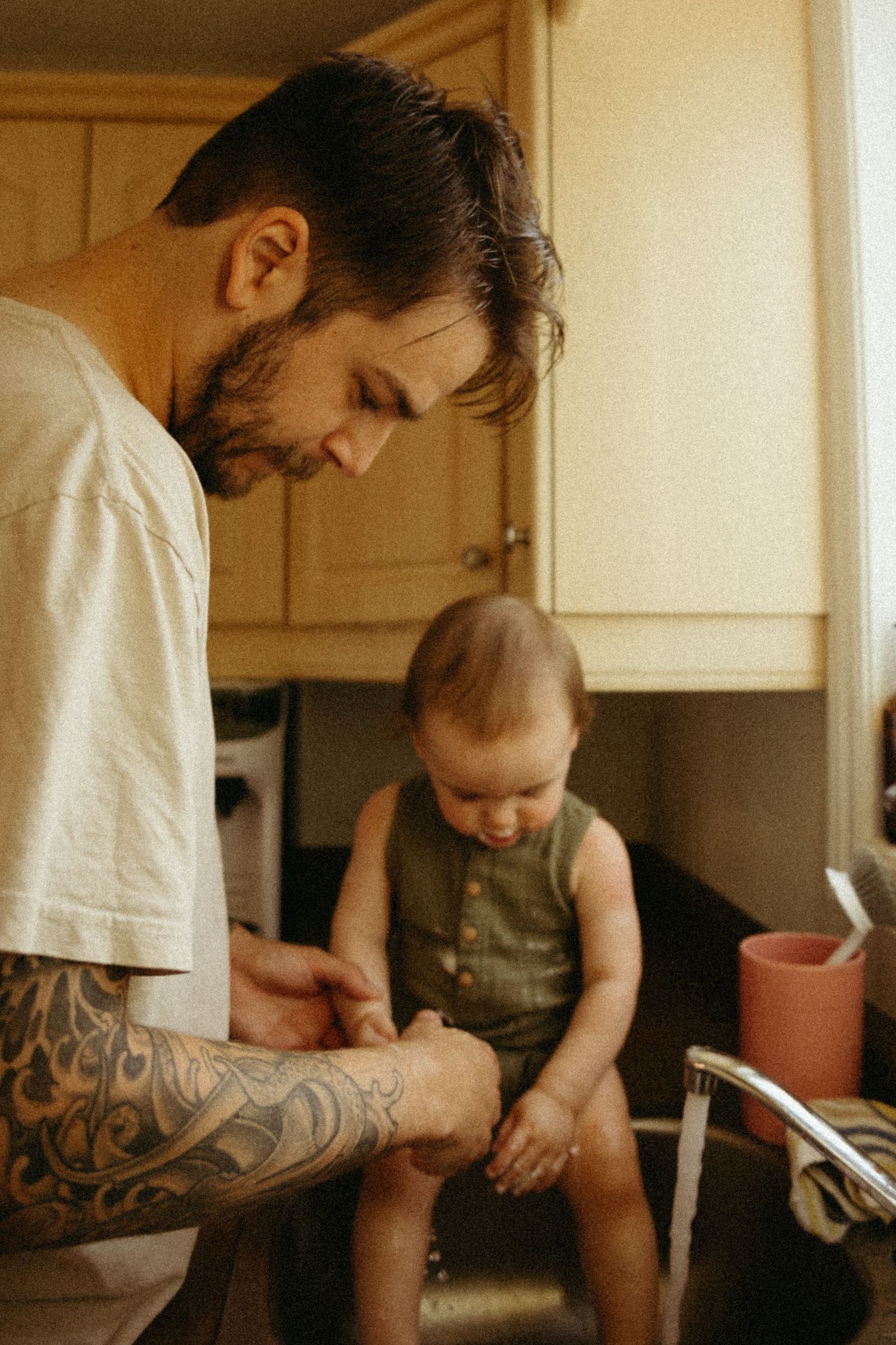Close-up shots of parent with tattoos reading to baby in casual home setting.