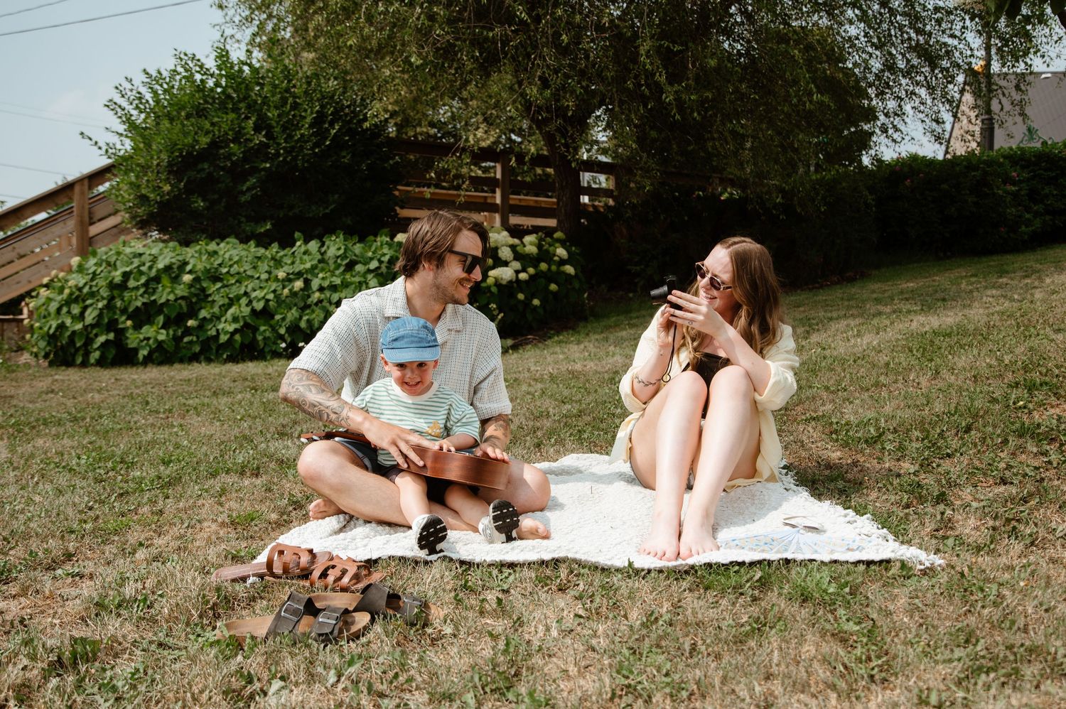 People lounging on blankets in a park with trees and greenery in the background.