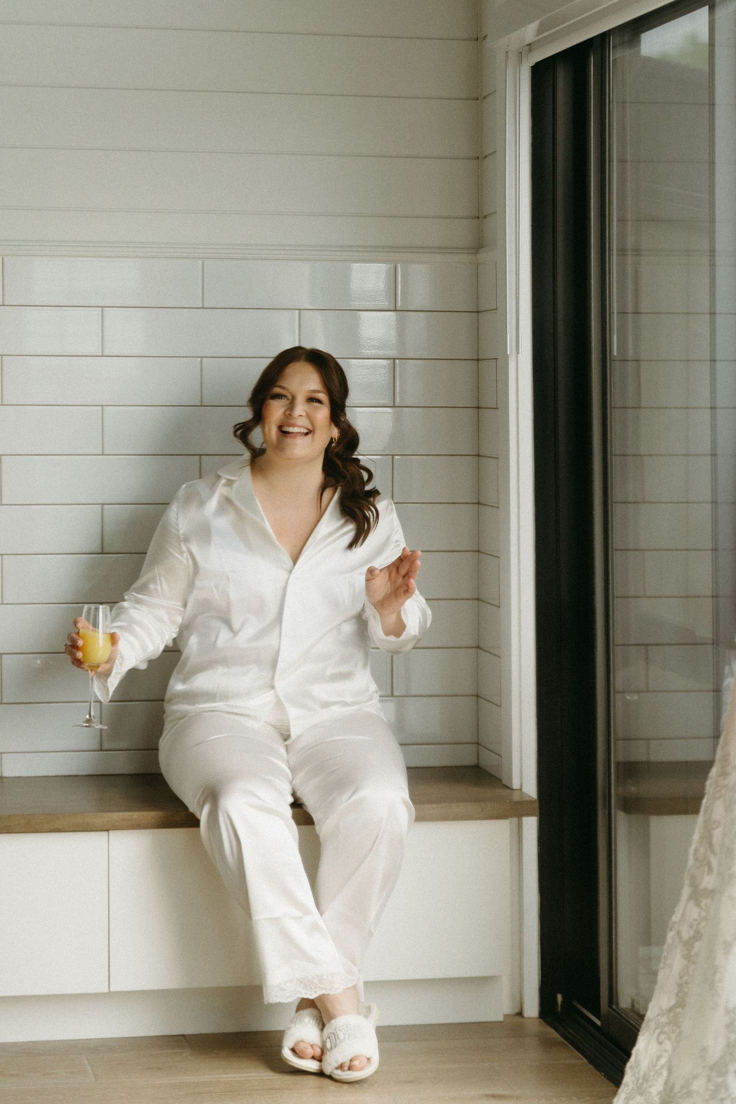 A person in a white robe sits on white steps with a glass of orange juice, creating a bright and relaxing scene.