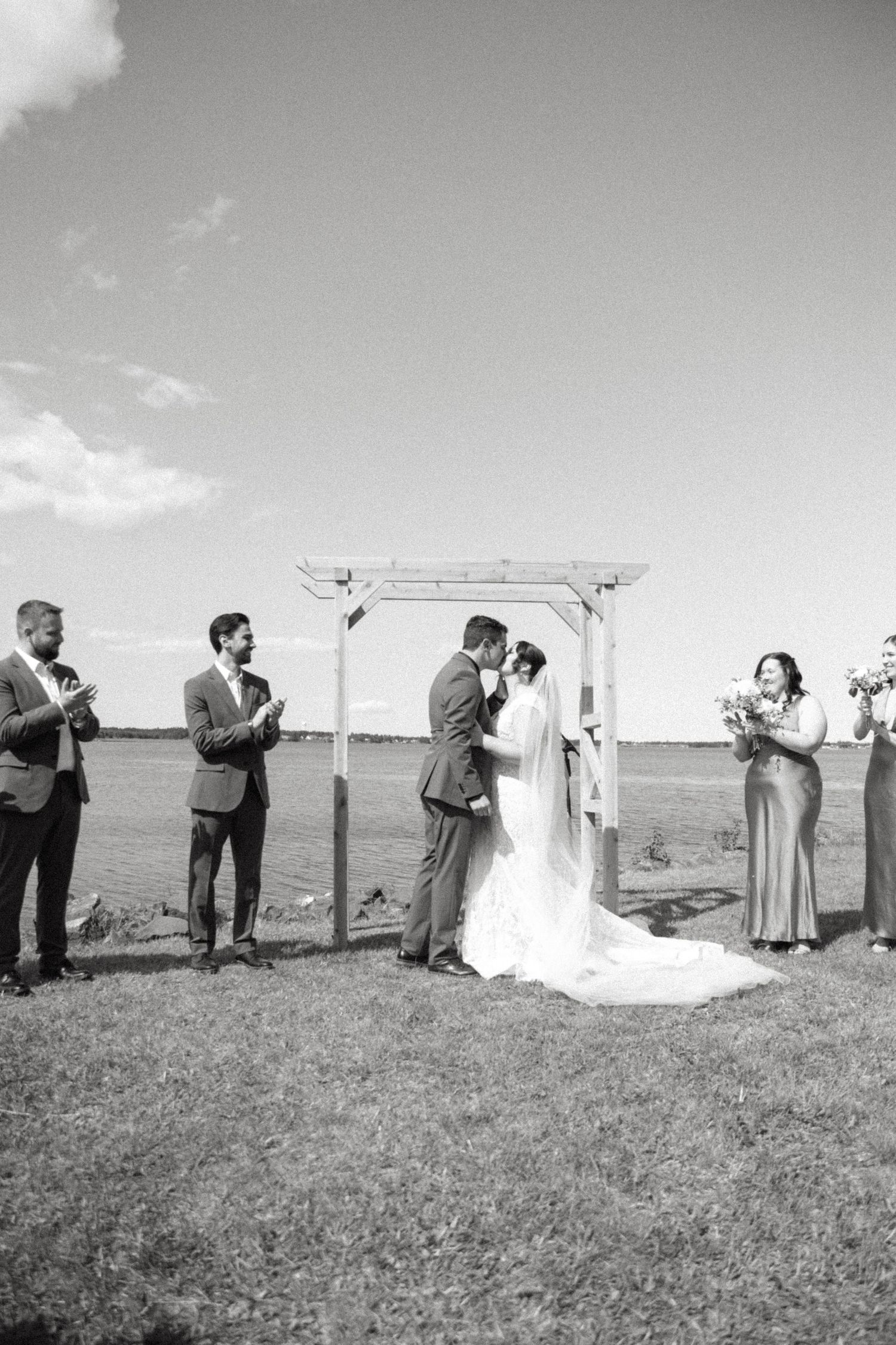 A sequence of black and white photos showing people taking photographs on a grassy hillside.