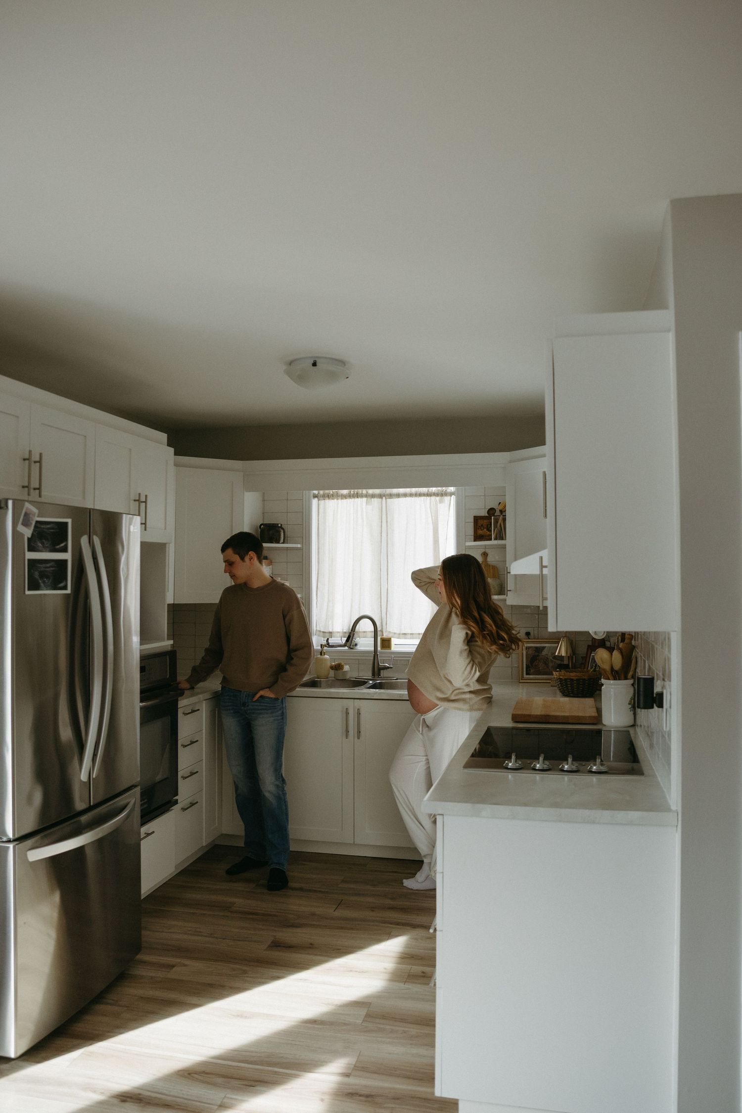 Modern white kitchen interior with wood flooring shown in a sequence of connected photos displaying natural light.