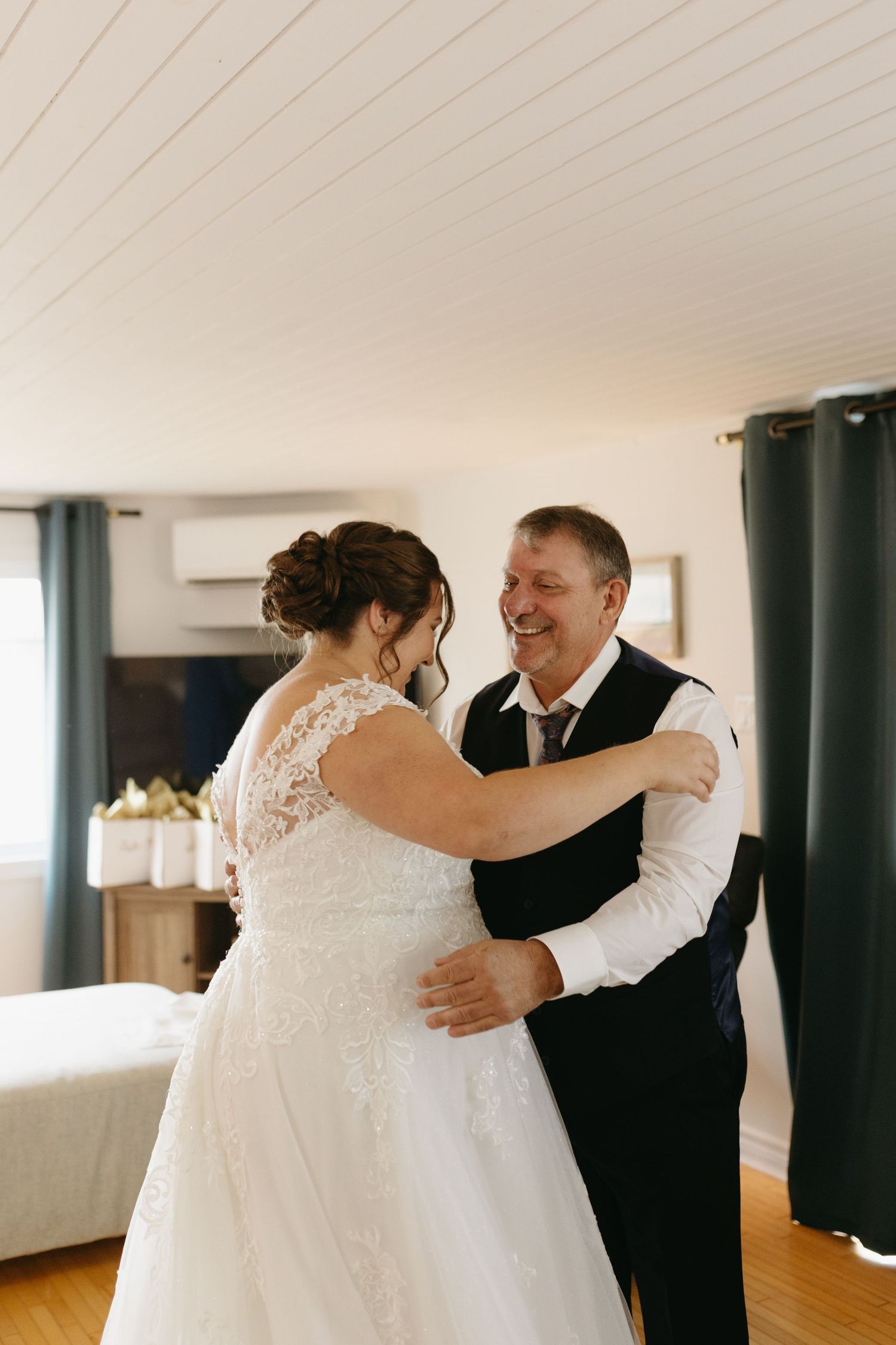 A couple shares a joyful dance moment during their wedding celebration in a bright indoor venue.