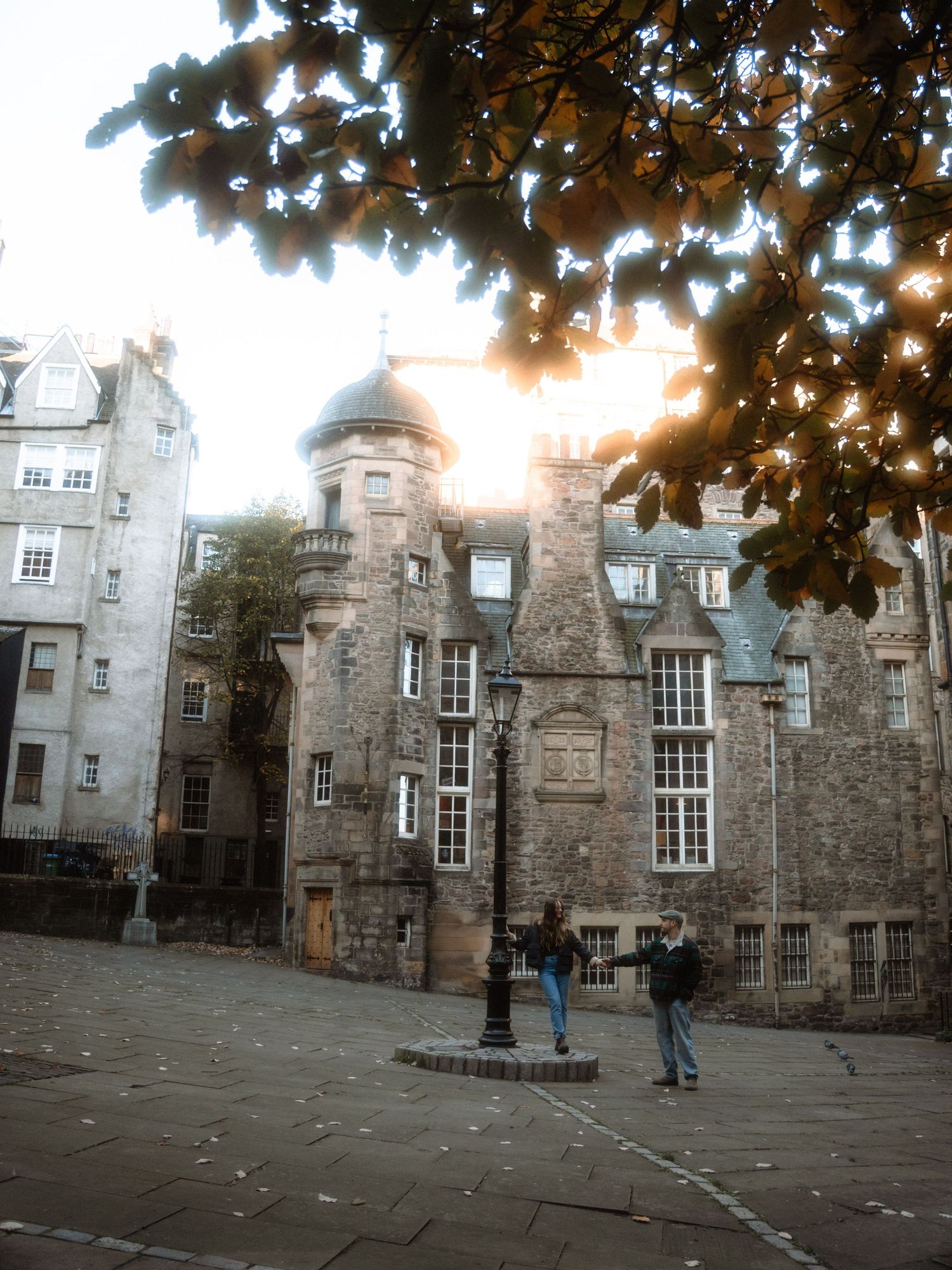 Historic stone castle courtyard with autumn leaves and visitors exploring the medieval architecture in Edinburgh.