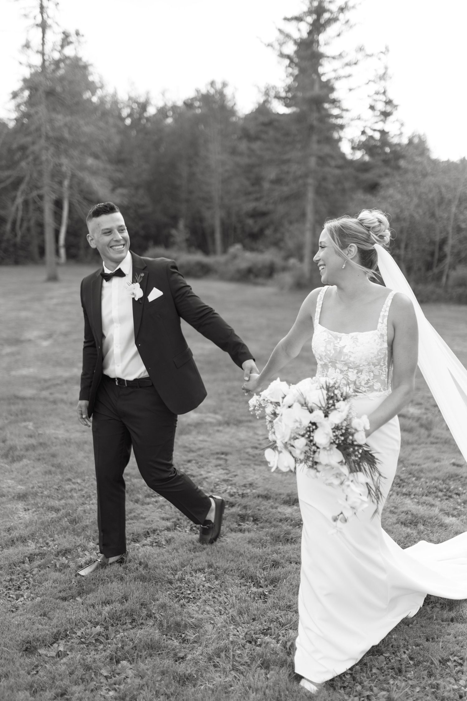 Playful black and white wedding photos of a couple dancing in a field.