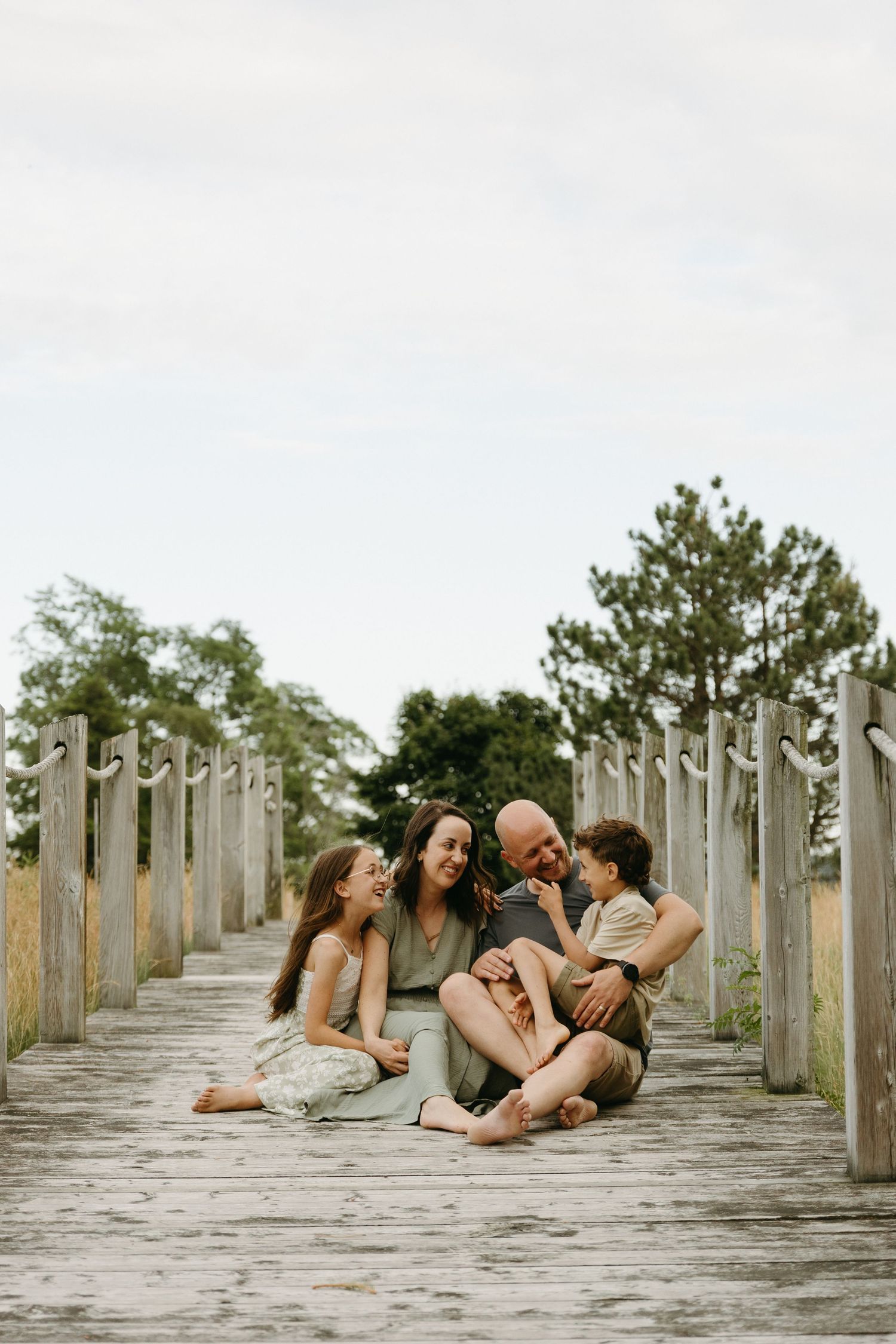 A group lounges together on a wooden pier with weathered posts stretching into the distance.
