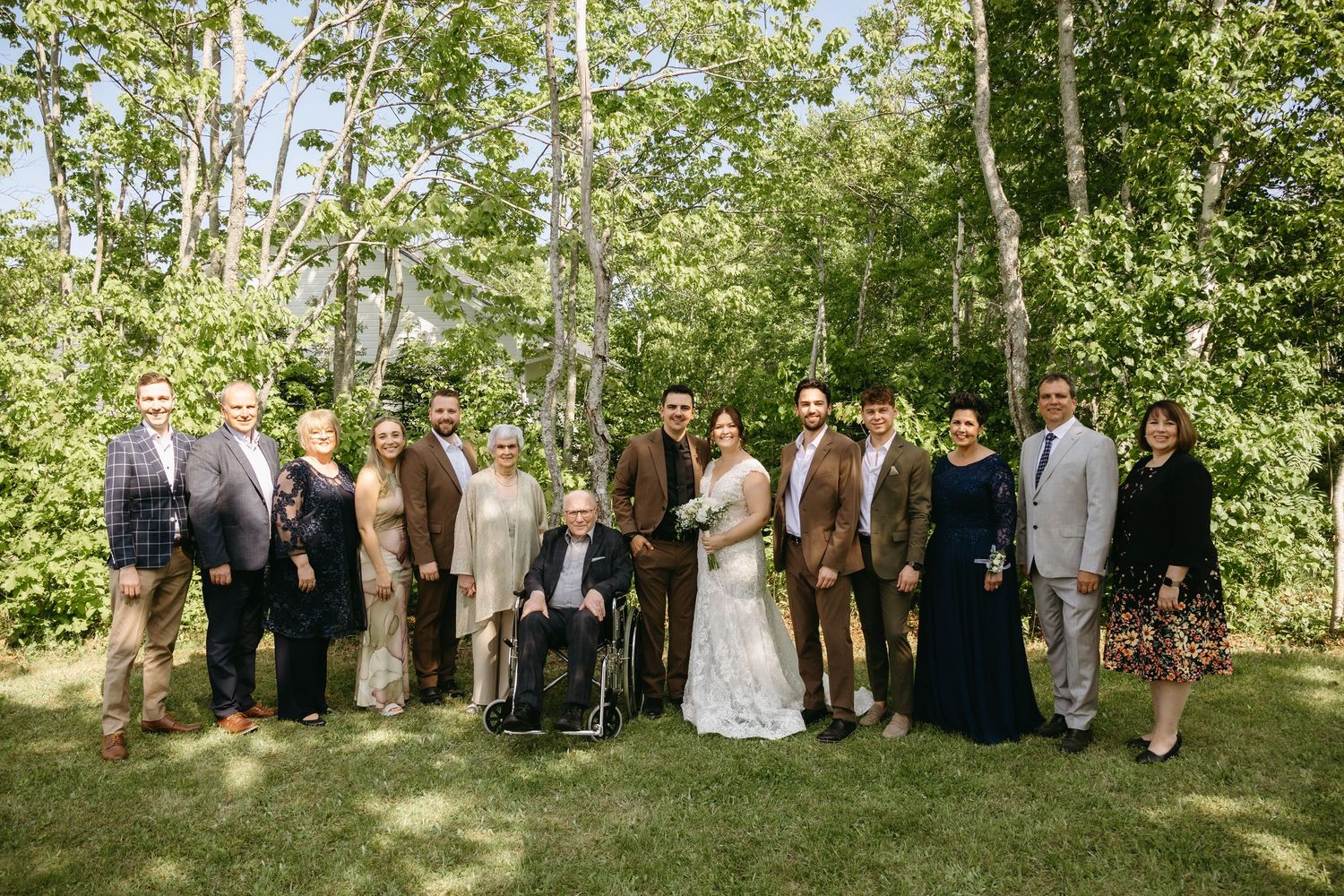 Wedding party poses together in a lush garden setting during an outdoor summer celebration.