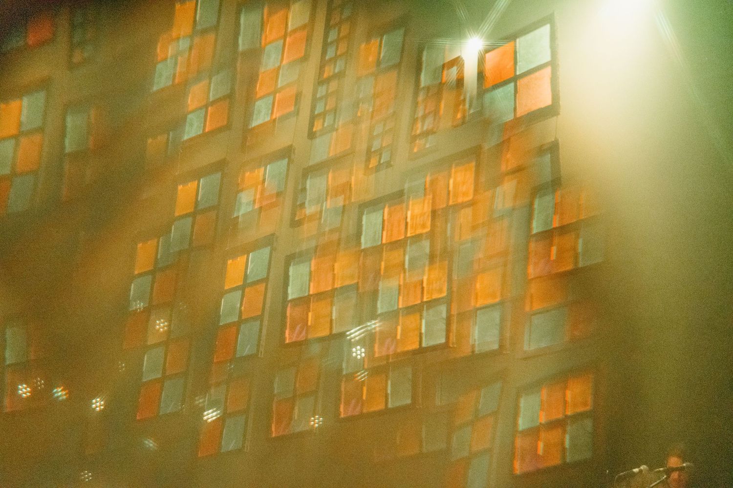 Orange post-it notes arranged in a grid pattern on a wall with green lighting effects.