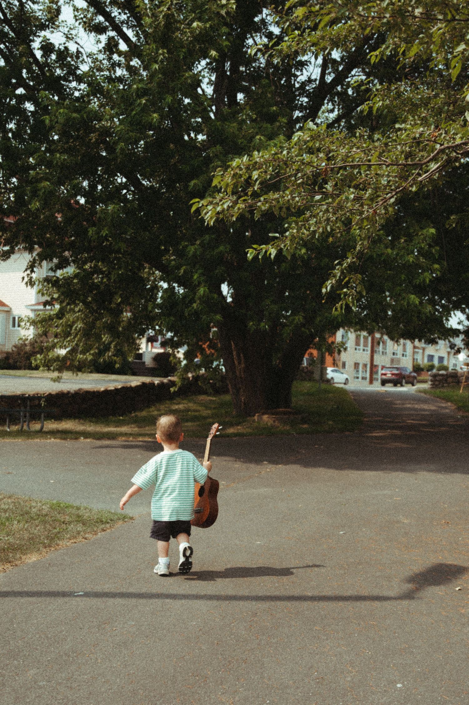 Sequence of child running across empty parking lot on sunny day with trees in background.