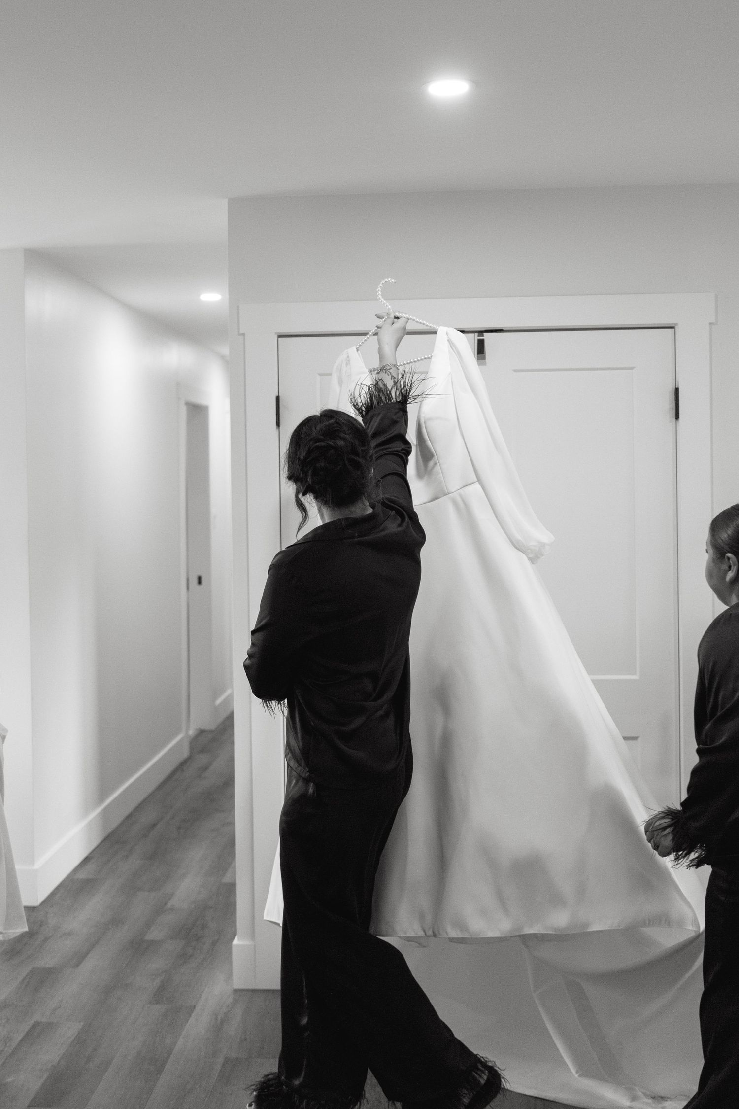 Black and white sequence showing someone hanging a white sheet or fabric in a hallway.