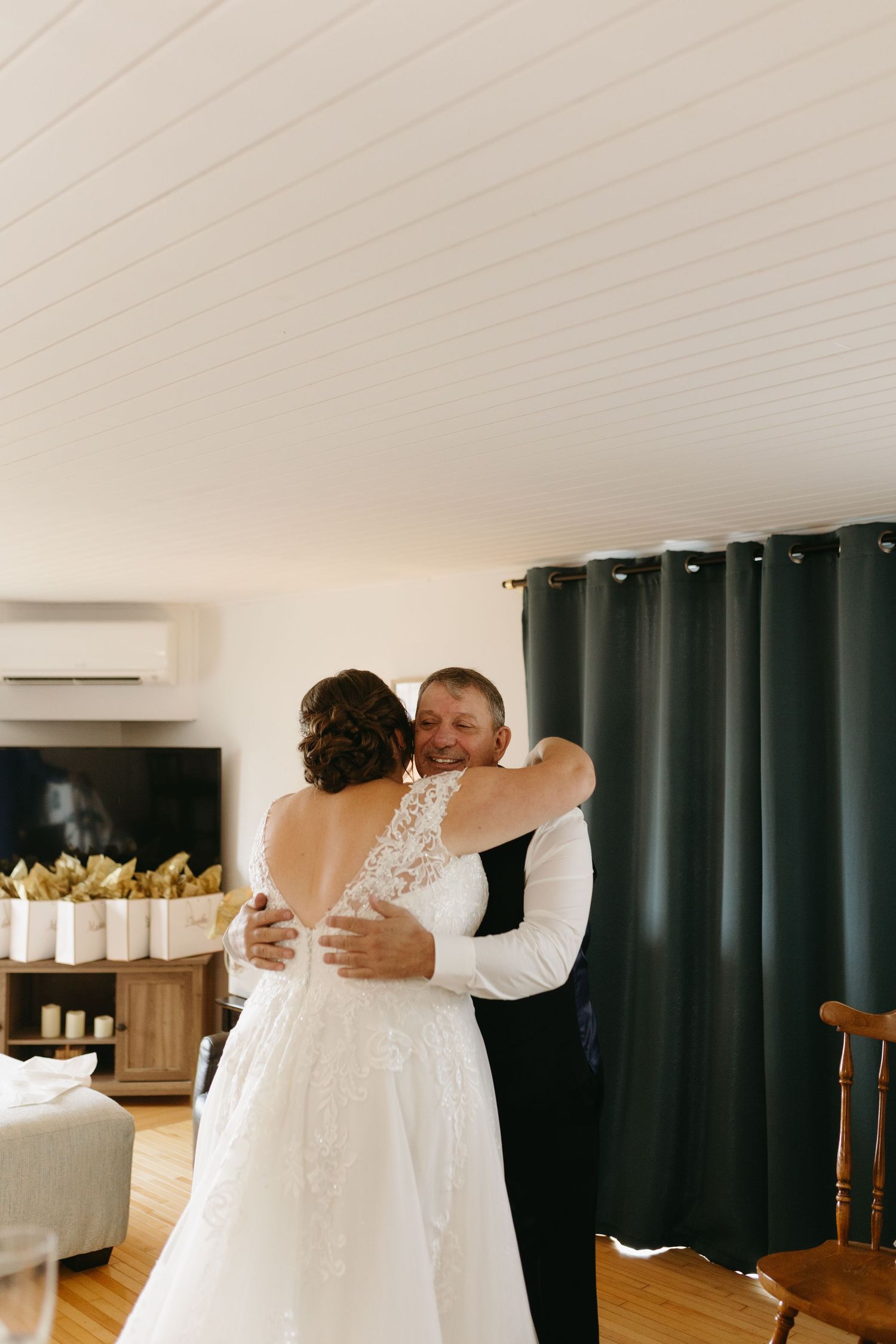 A heartwarming moment captured as two people in white dresses embrace during what appears to be a wedding preparation.