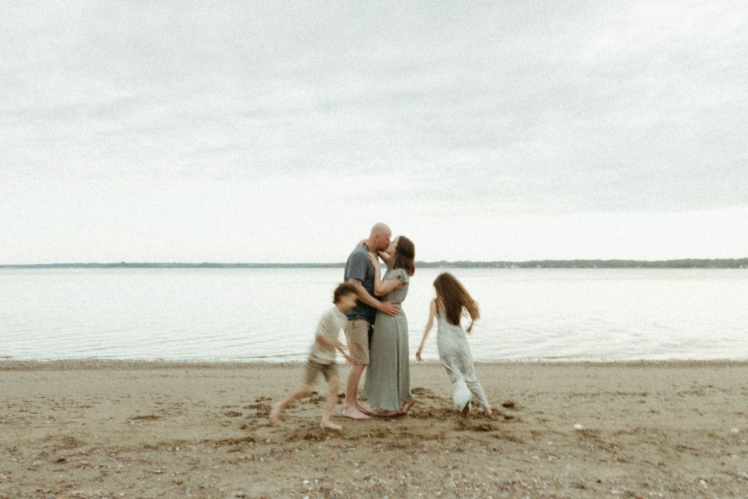 Romantic moment shared between two people on a peaceful sandy beach with cloudy skies above.