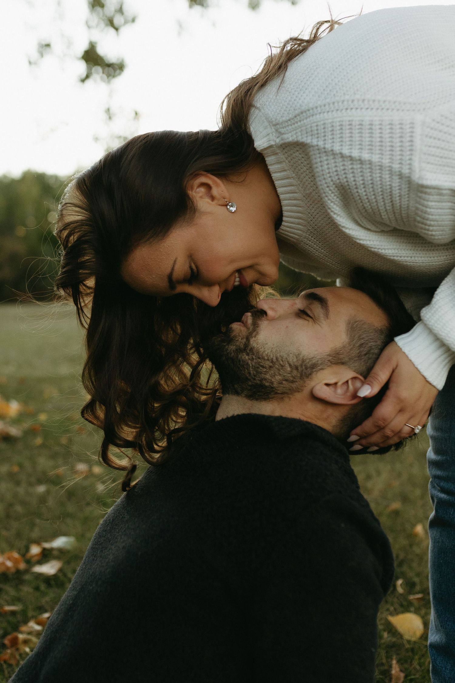 A romantic outdoor portrait of a couple sharing an intimate moment in autumn with warm lighting and fallen leaves.