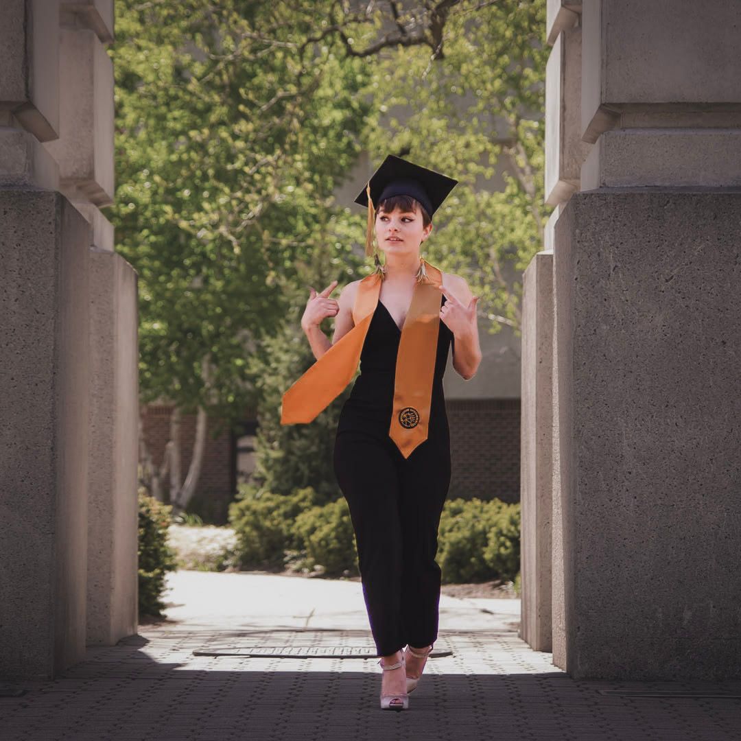 Shay Godfrey photographing a college graduate in cap and gown outdoors