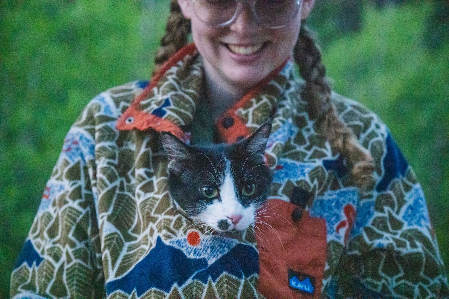 Shay Godfrey photographing a cat in owners hoodie peeking out.