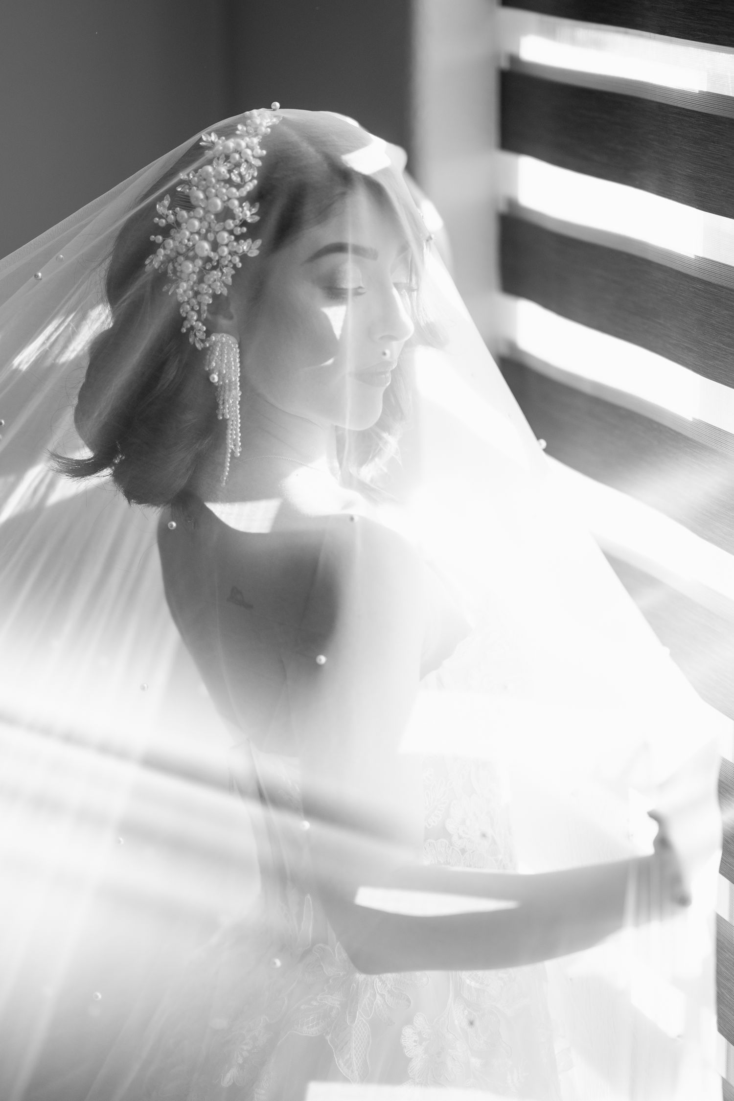 Ethereal bridal portraits in dramatic window light showing wedding veil and headpiece details.