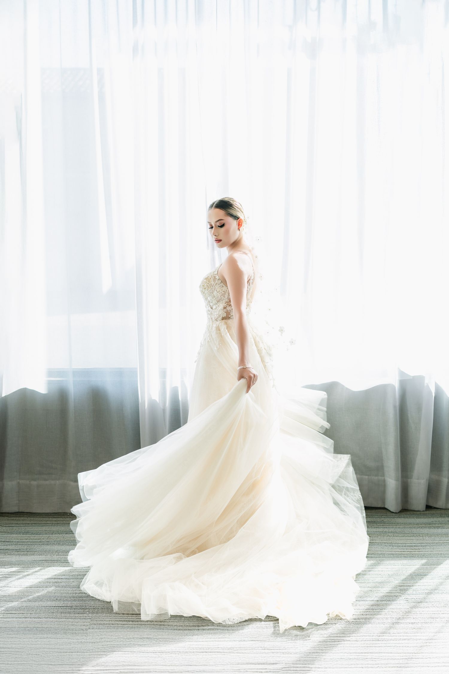 Ethereal bridal portrait with flowing white gown against soft window light.