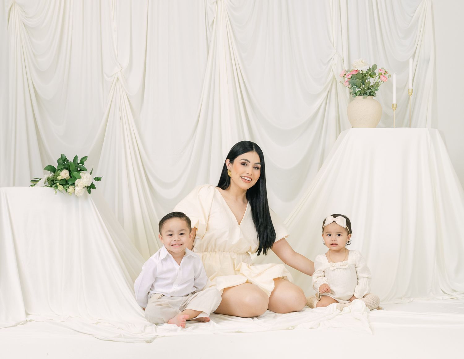 Family portrait with mother and two children in matching cream outfits.