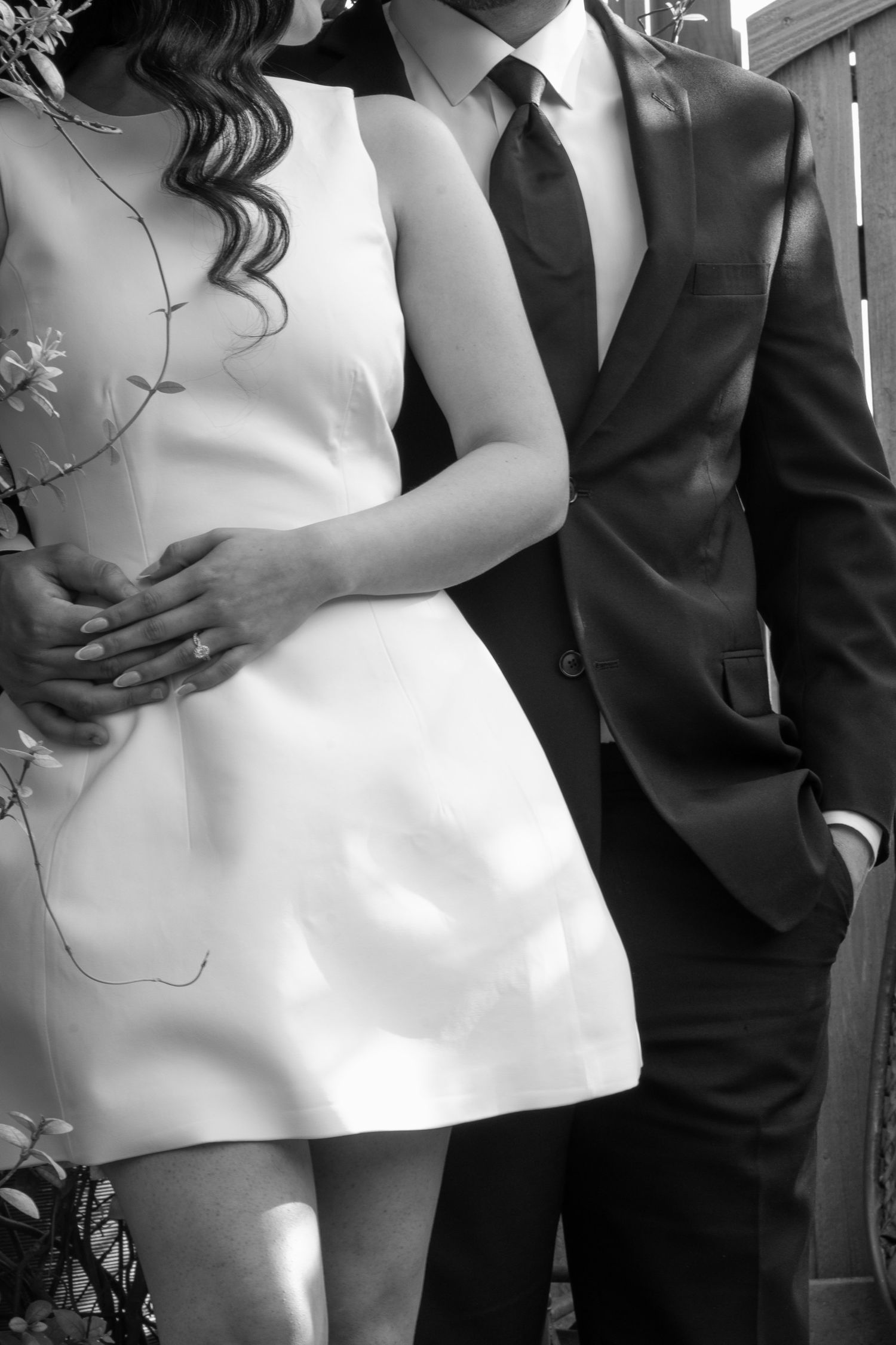 Black and white close-up of couple featuring wedding dress and suit details.