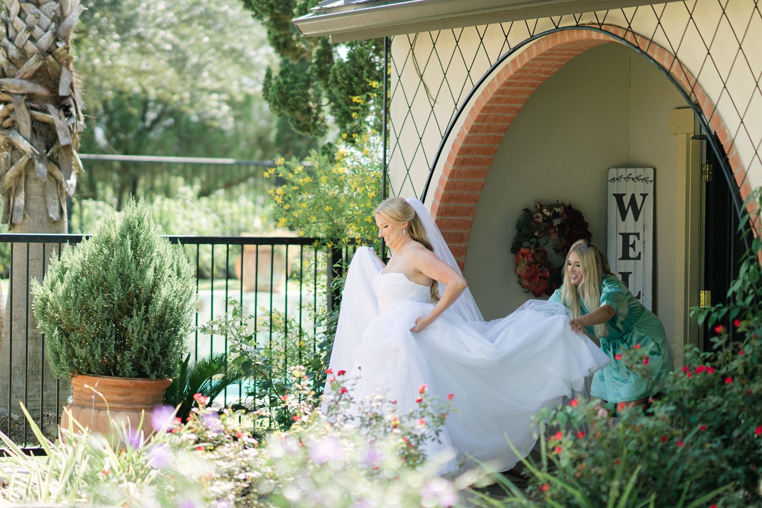 Ethereal bridal portrait with flowing white dress in garden archway setting.
