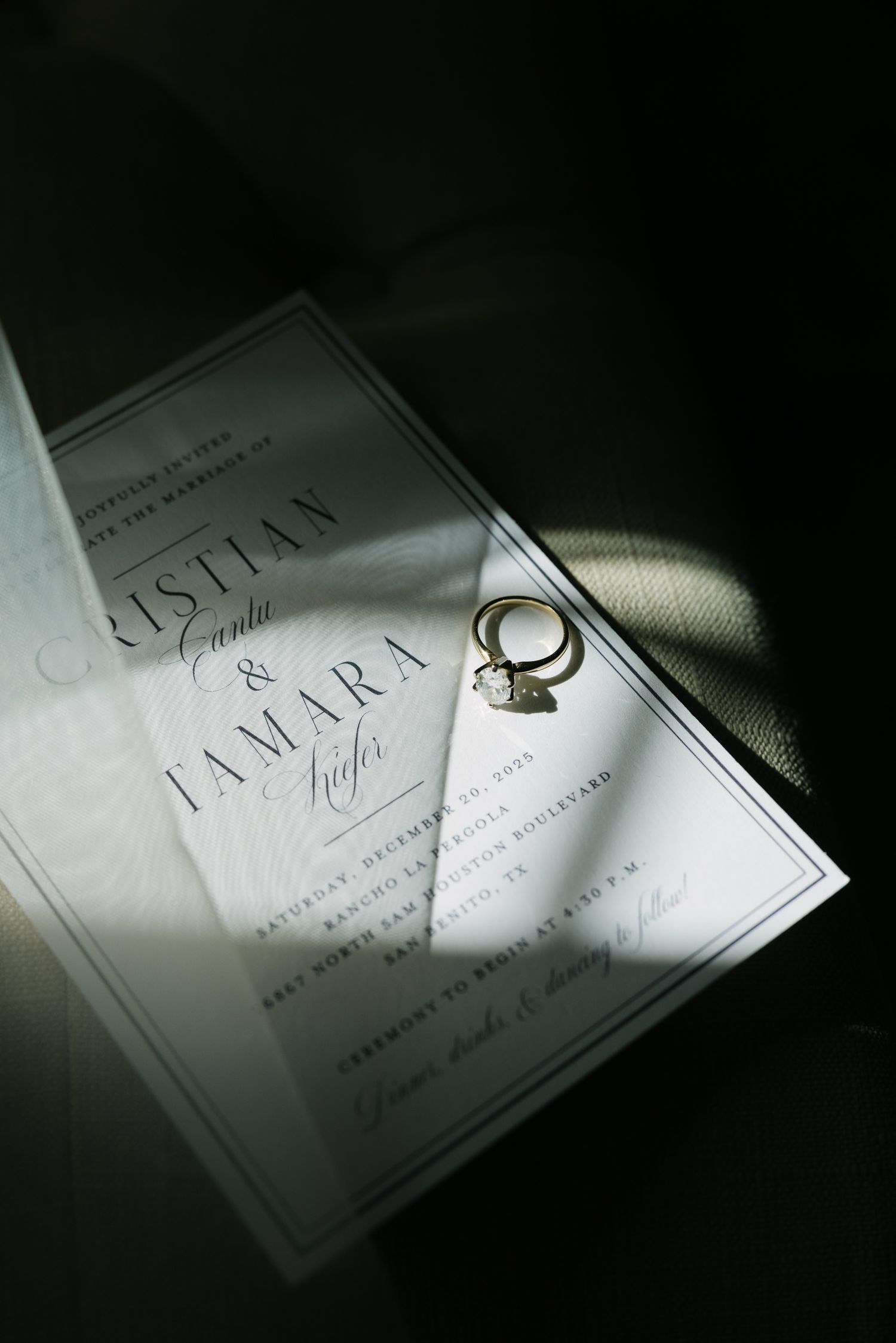 Elegant wedding invitation suite with gold diamond engagement ring resting on white stationery for Cristian and Tamara.