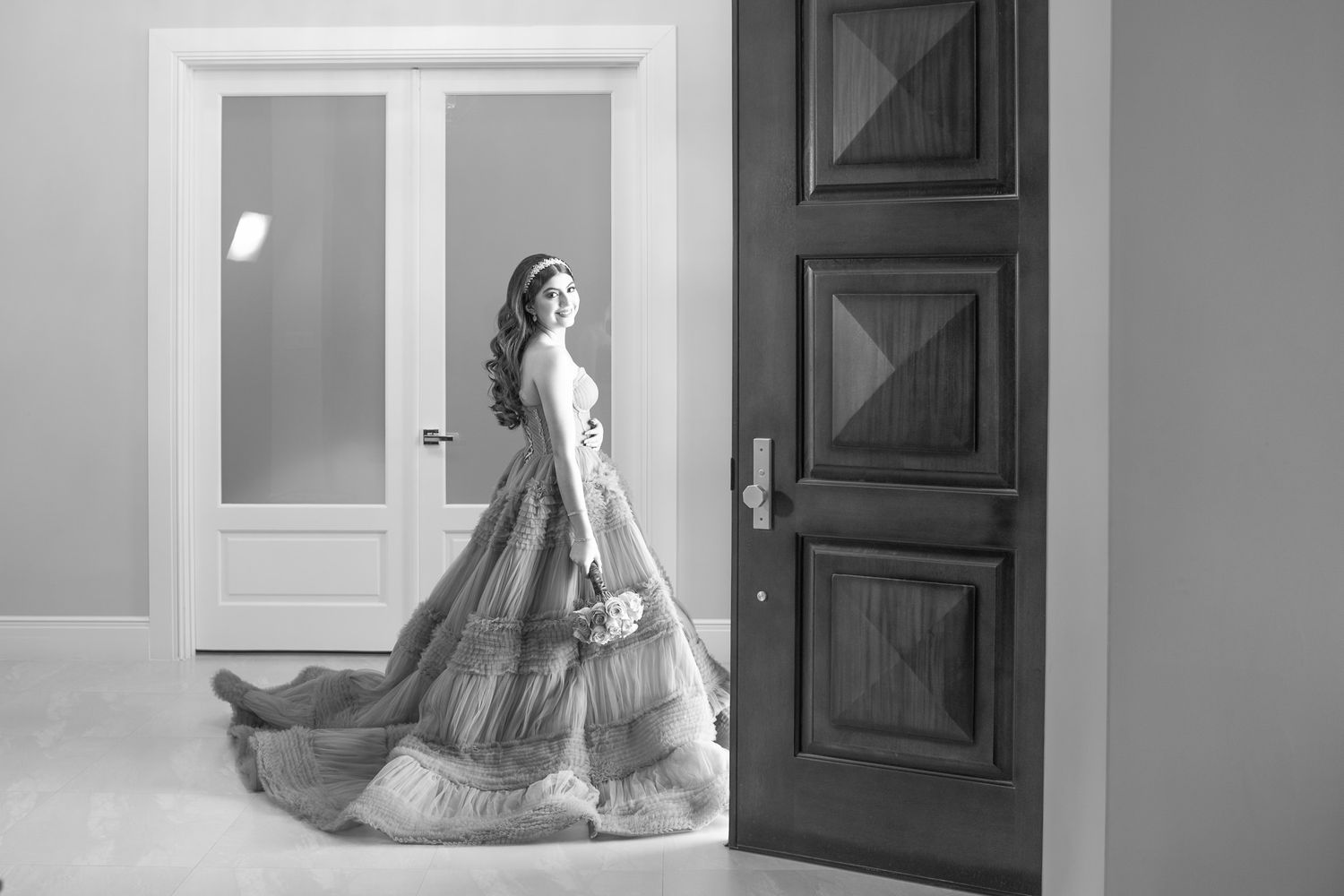 Elegant black and white wedding photos featuring a bride in a flowing gown against white doors and windows.