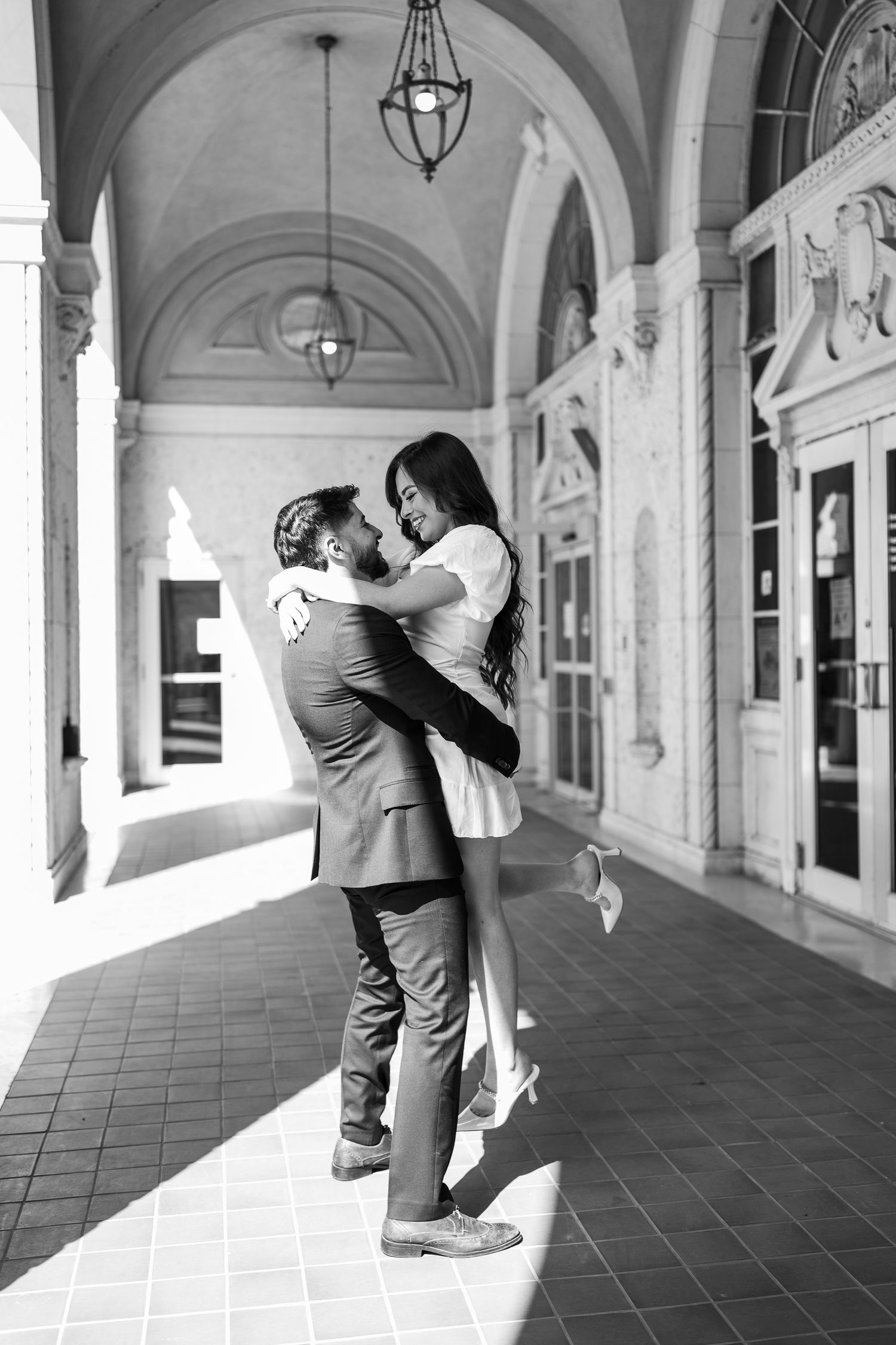 A romantic embrace in a grand arched hallway with classic architectural details.