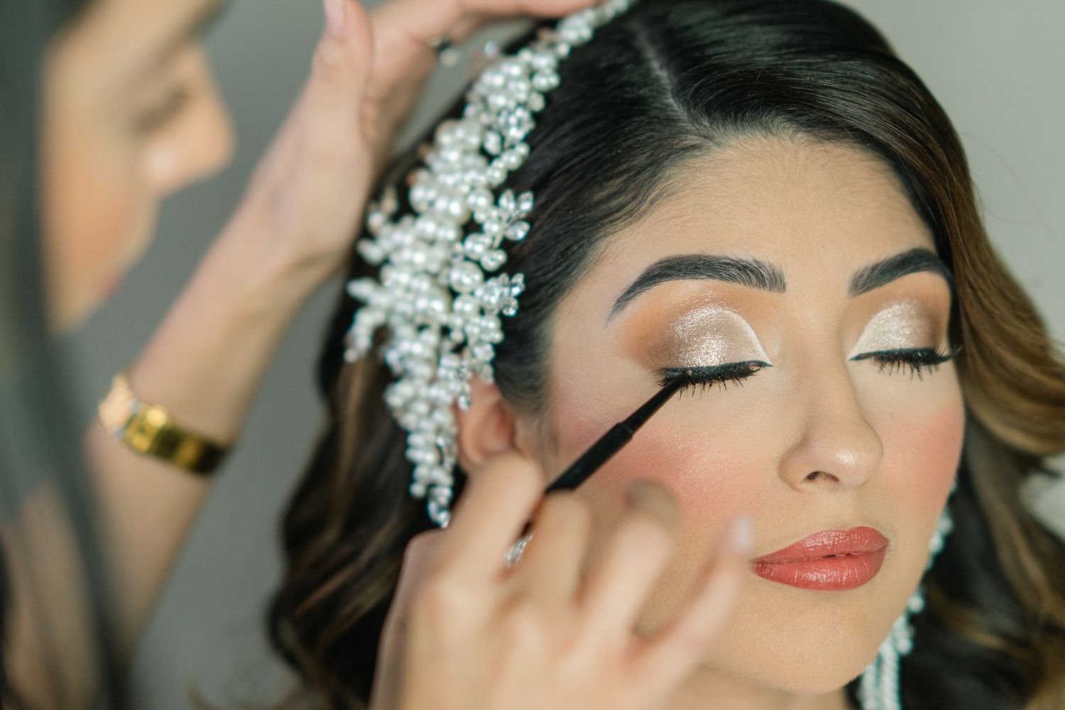 Professional makeup application showing detailed eye makeup and crystal hair accessories.
