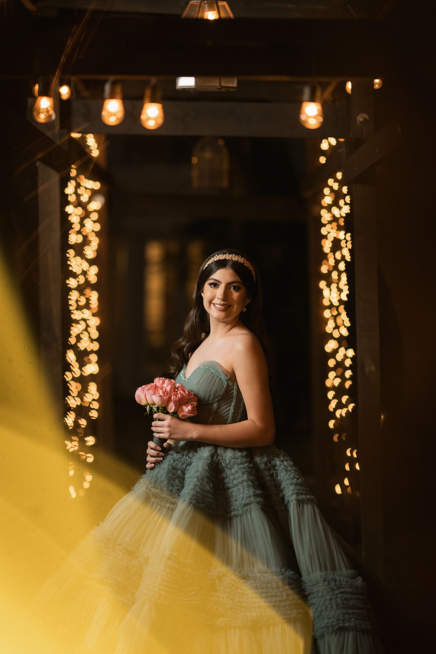 An enchanting portrait of someone in a blue gown holding flowers, surrounded by twinkling lights.