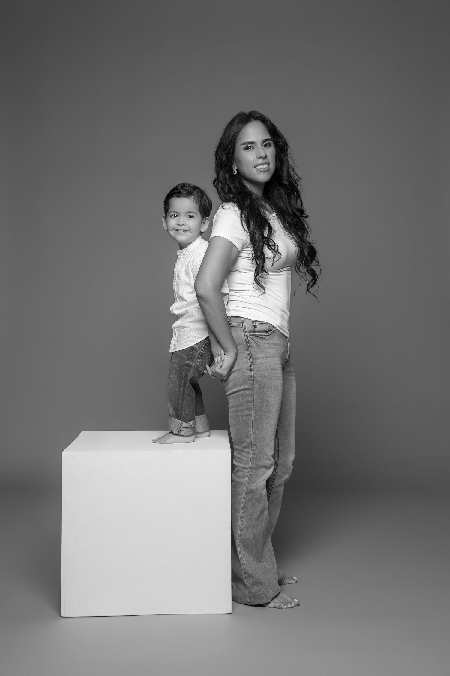 Black and white portrait of parent and child posing with white cube.