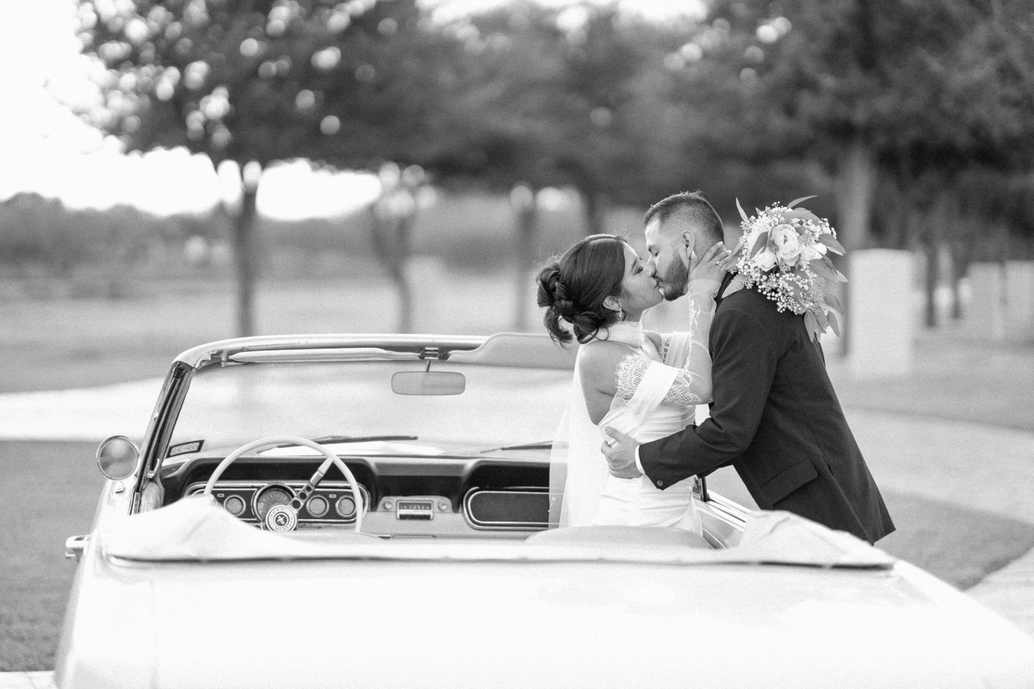 Black and white portrait of a couple in a classic convertible car.